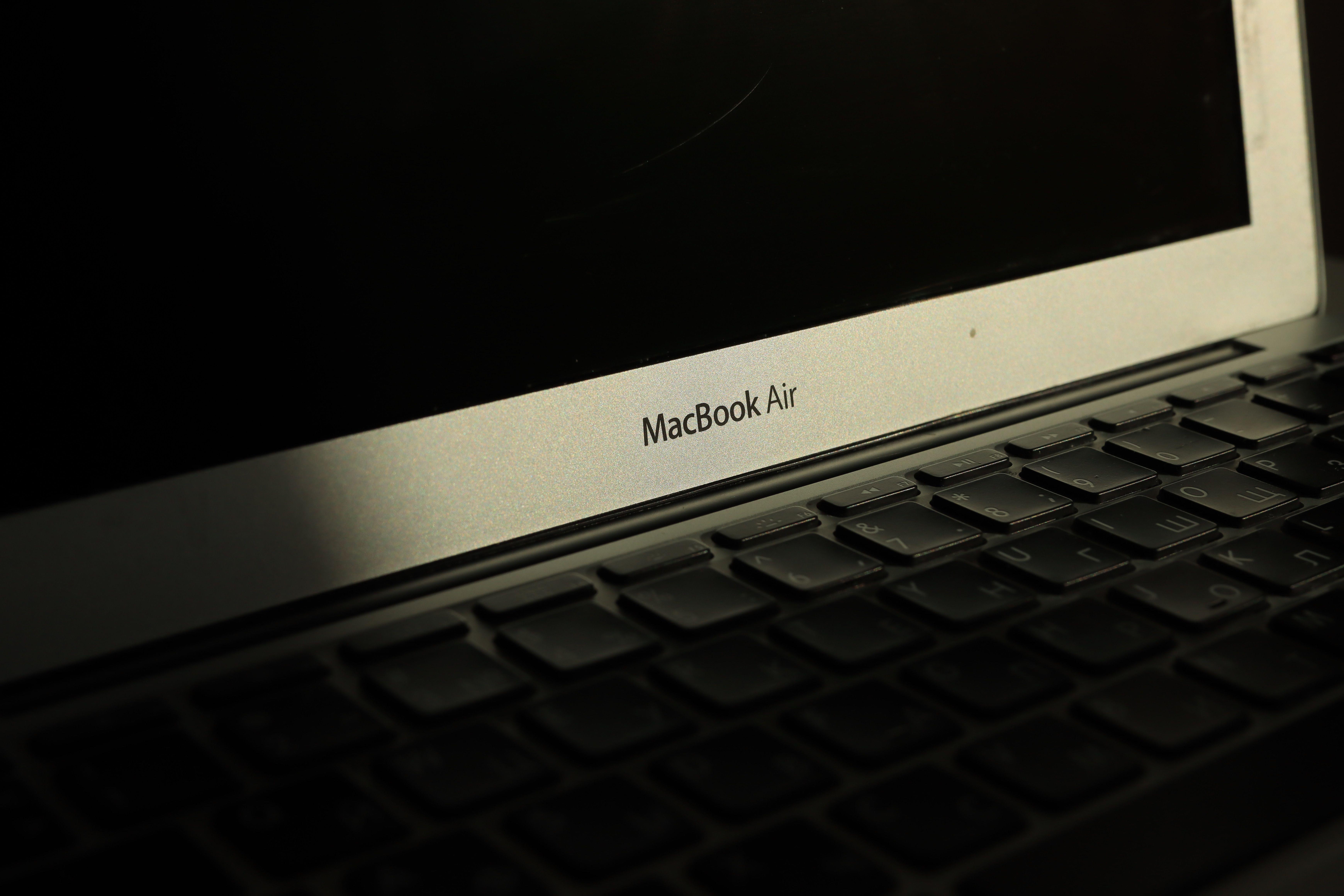 Close-up of a sunlit MacBook Air laptop showcasing its keyboard and screen with shadow effects.