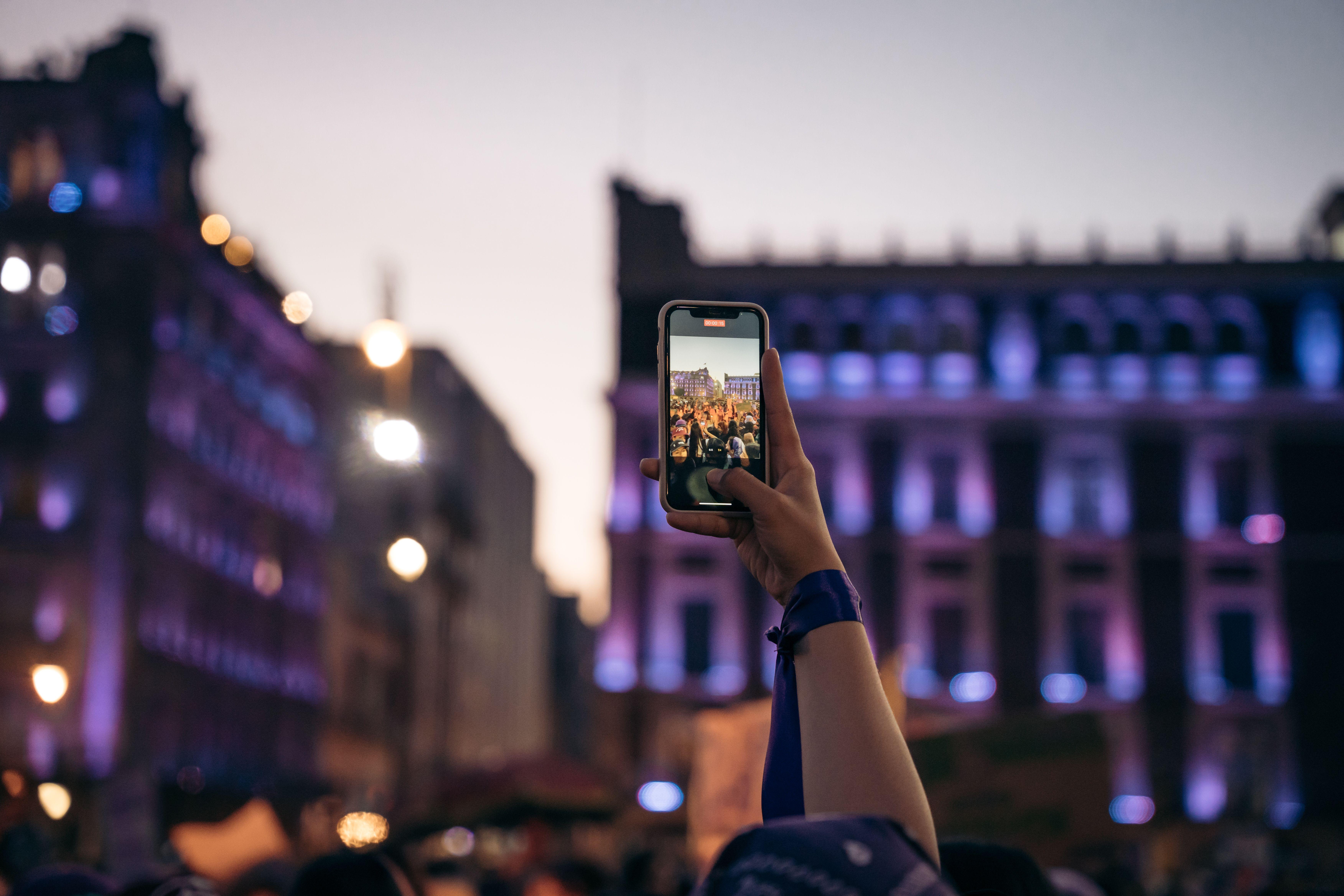 A lively evening scene in Mexico City with people enjoying the illuminated night using smartphones.