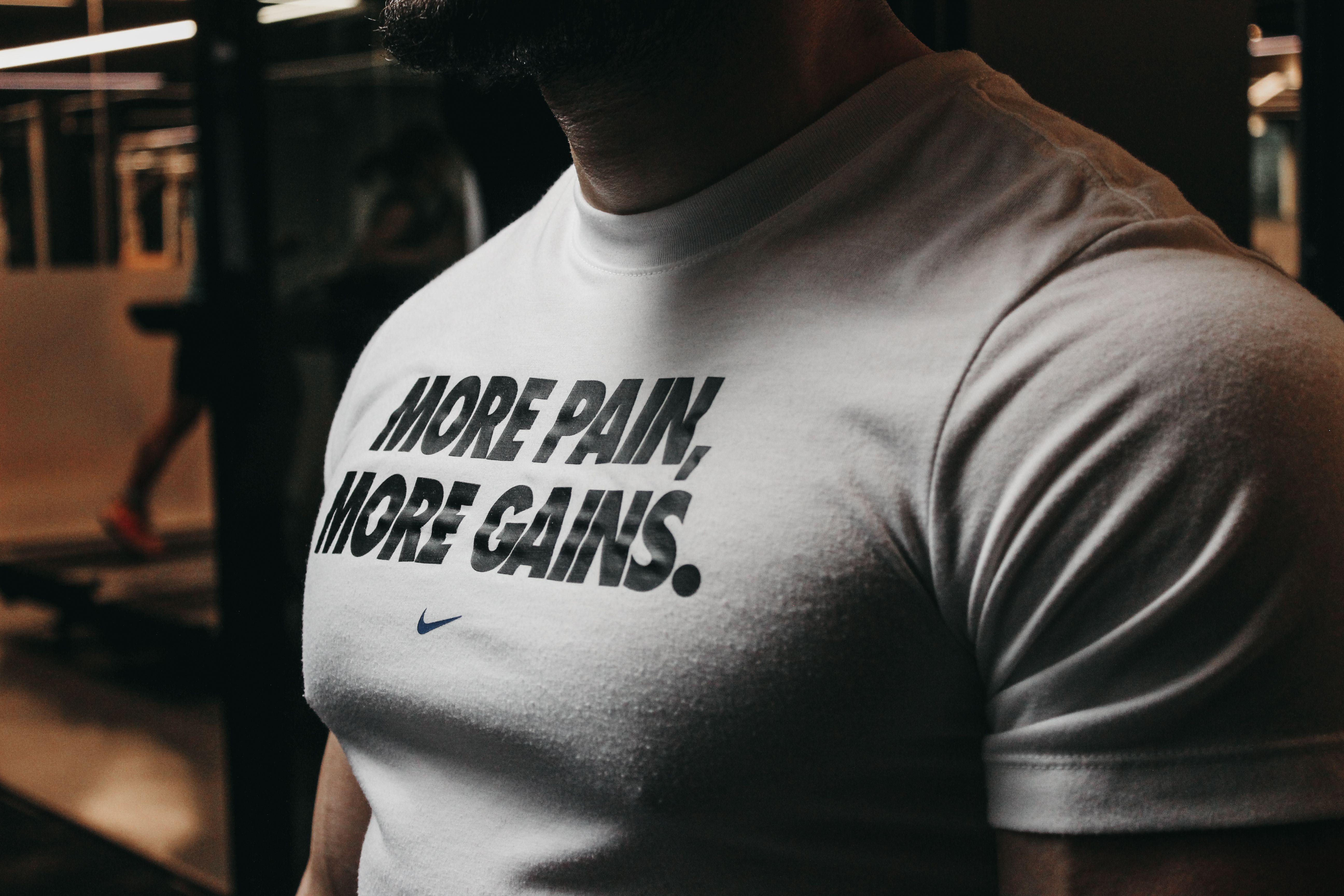 Close-up of a muscular man in the gym wearing a t-shirt with an inspiring fitness message.