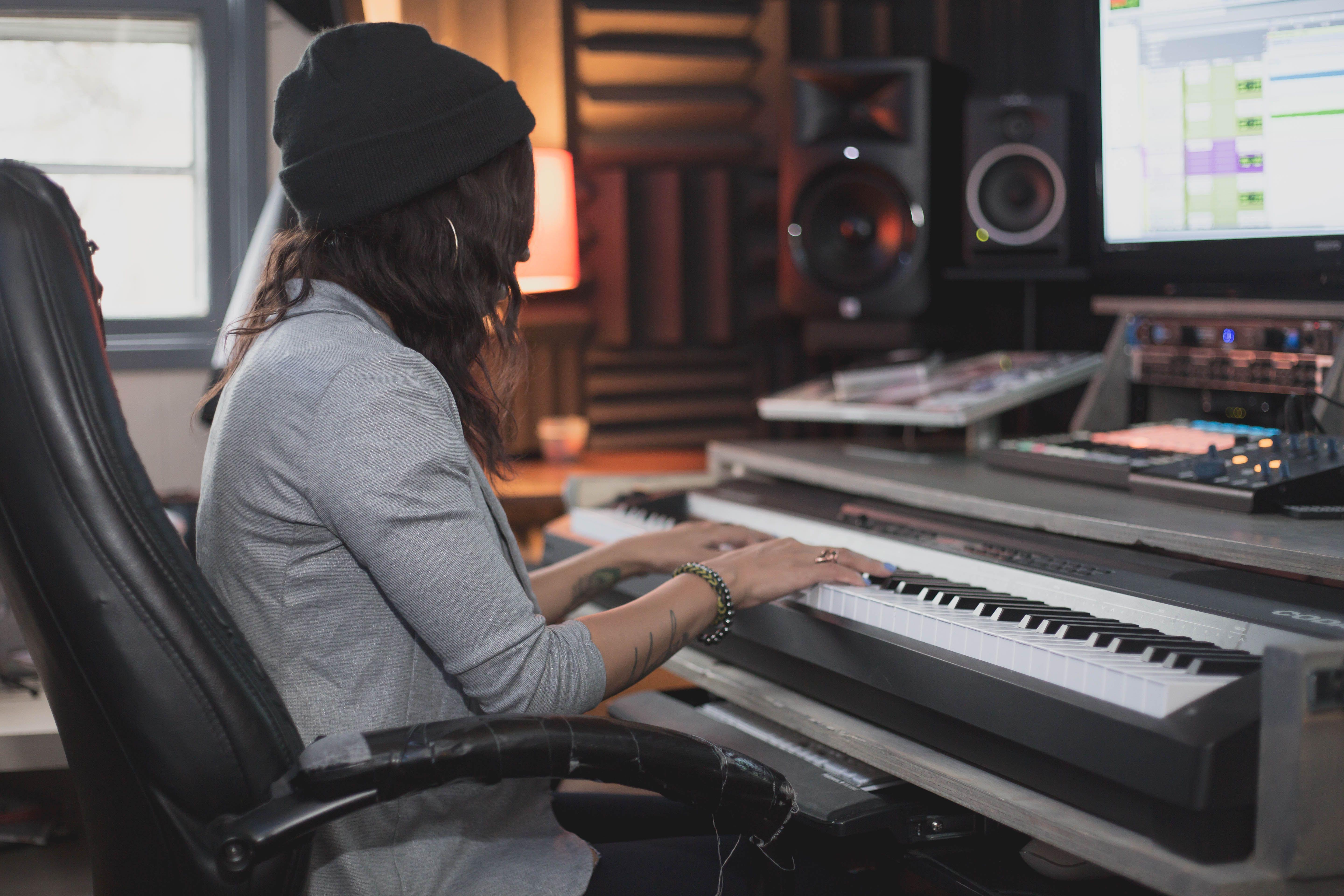 Woman with long hair playing keyboard in a professional music studio.