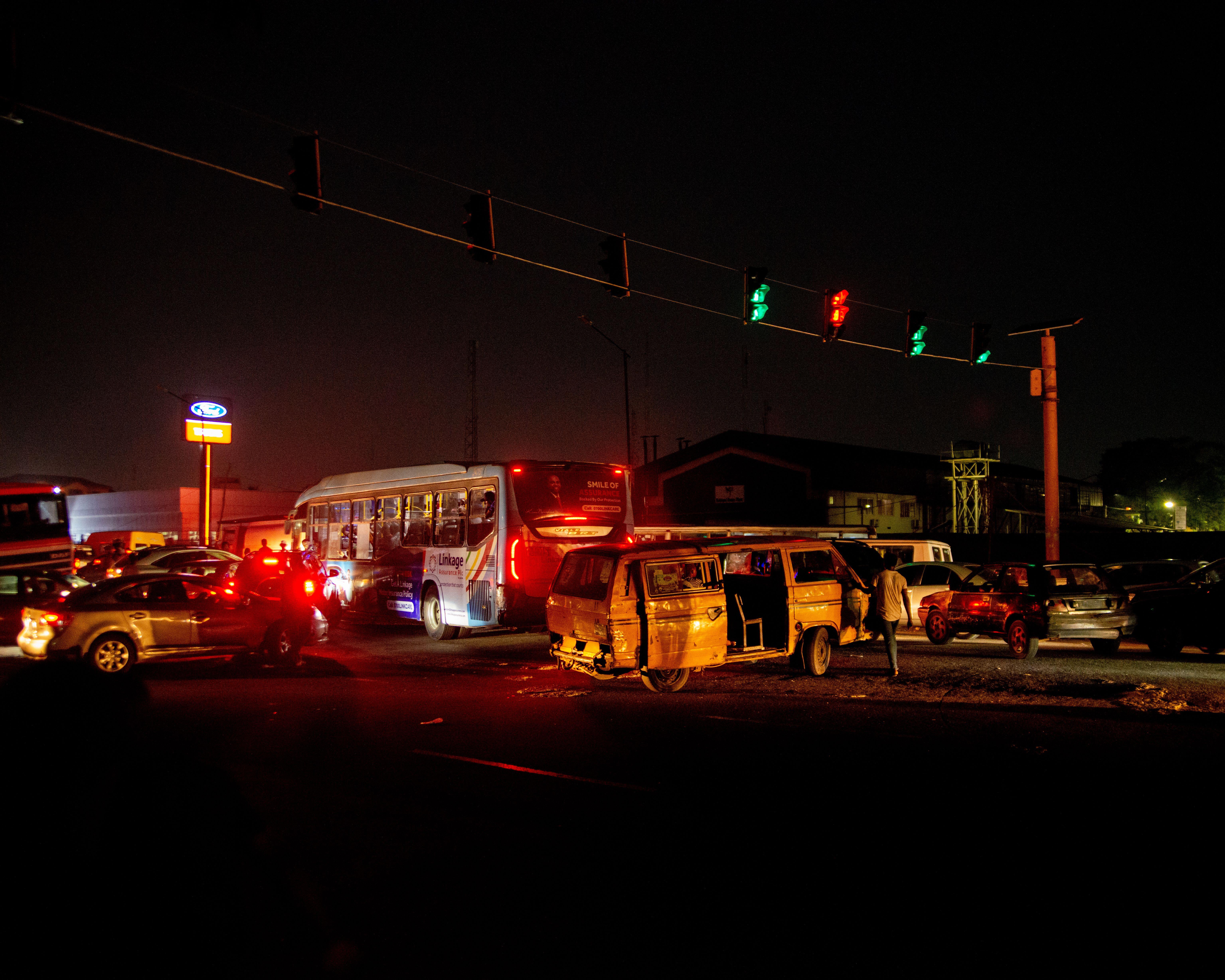 A crowded urban nighttime scene featuring a traffic accident at a busy intersection.