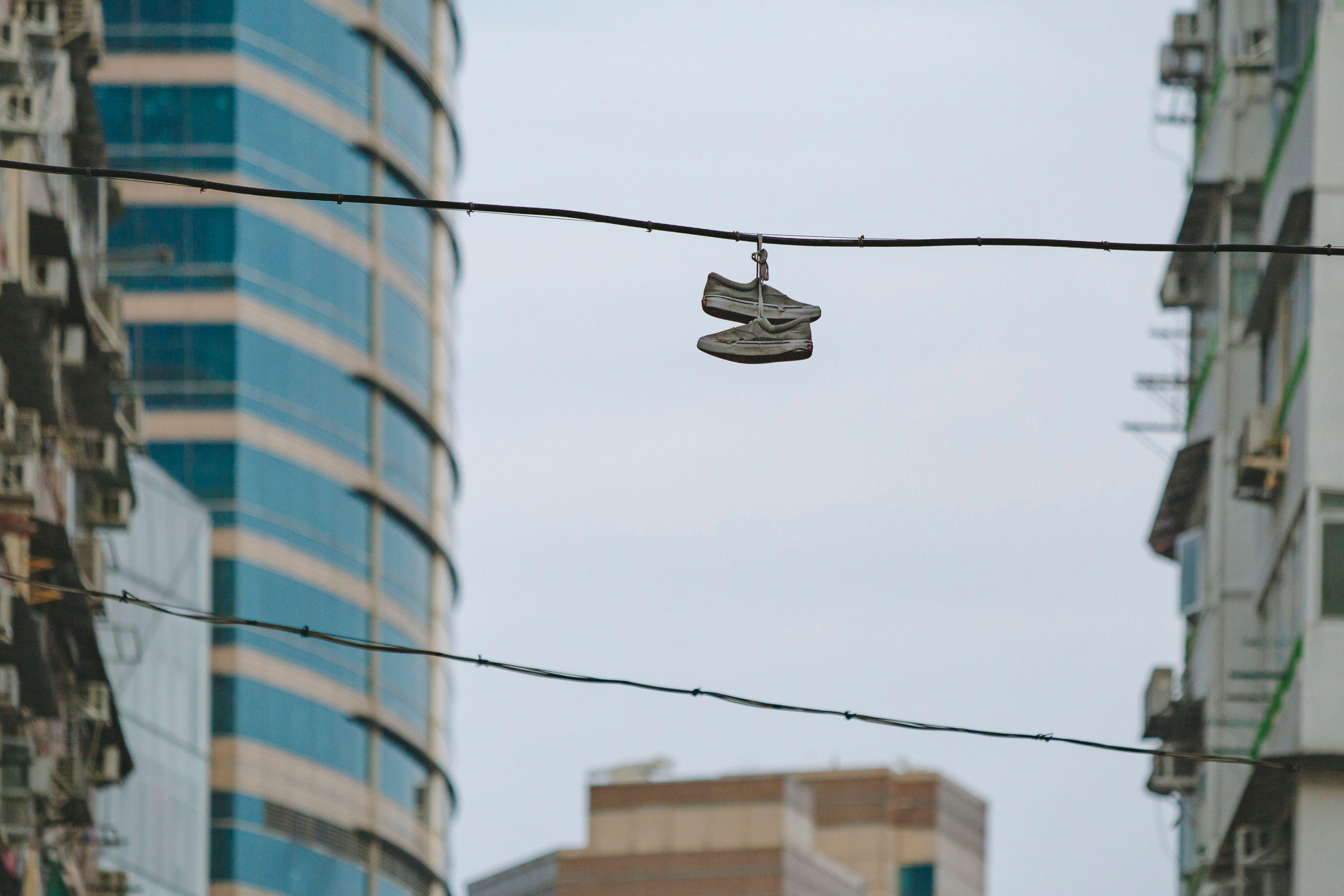 Sneakers hanging on wire amidst Hong Kong skyscrapers, showcasing urban lifestyle and architecture.