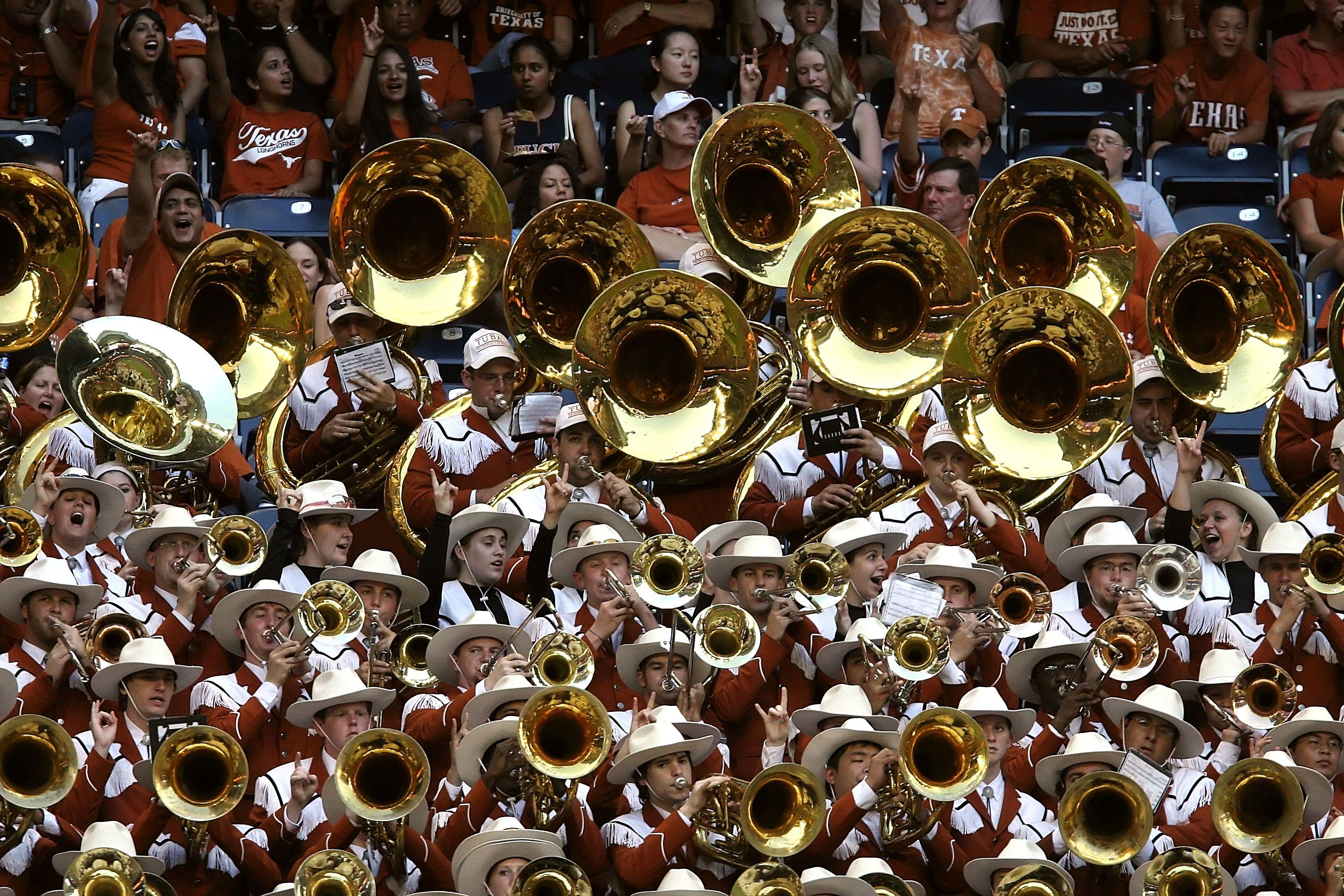 A lively marching band performs with brass instruments at a crowded sports stadium.