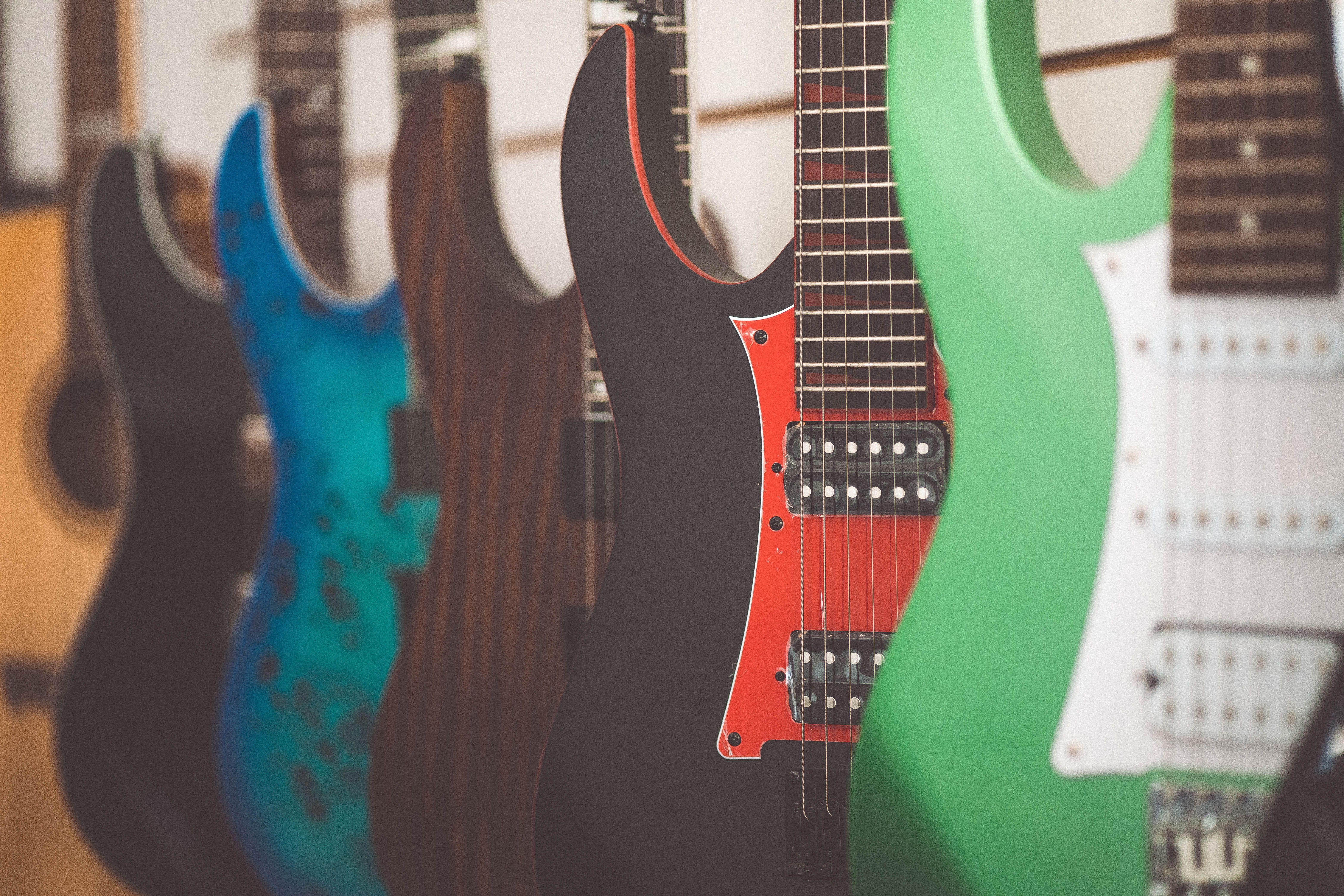 Colorful electric guitars lined up in a music store display, highlighting different styles and finishes.