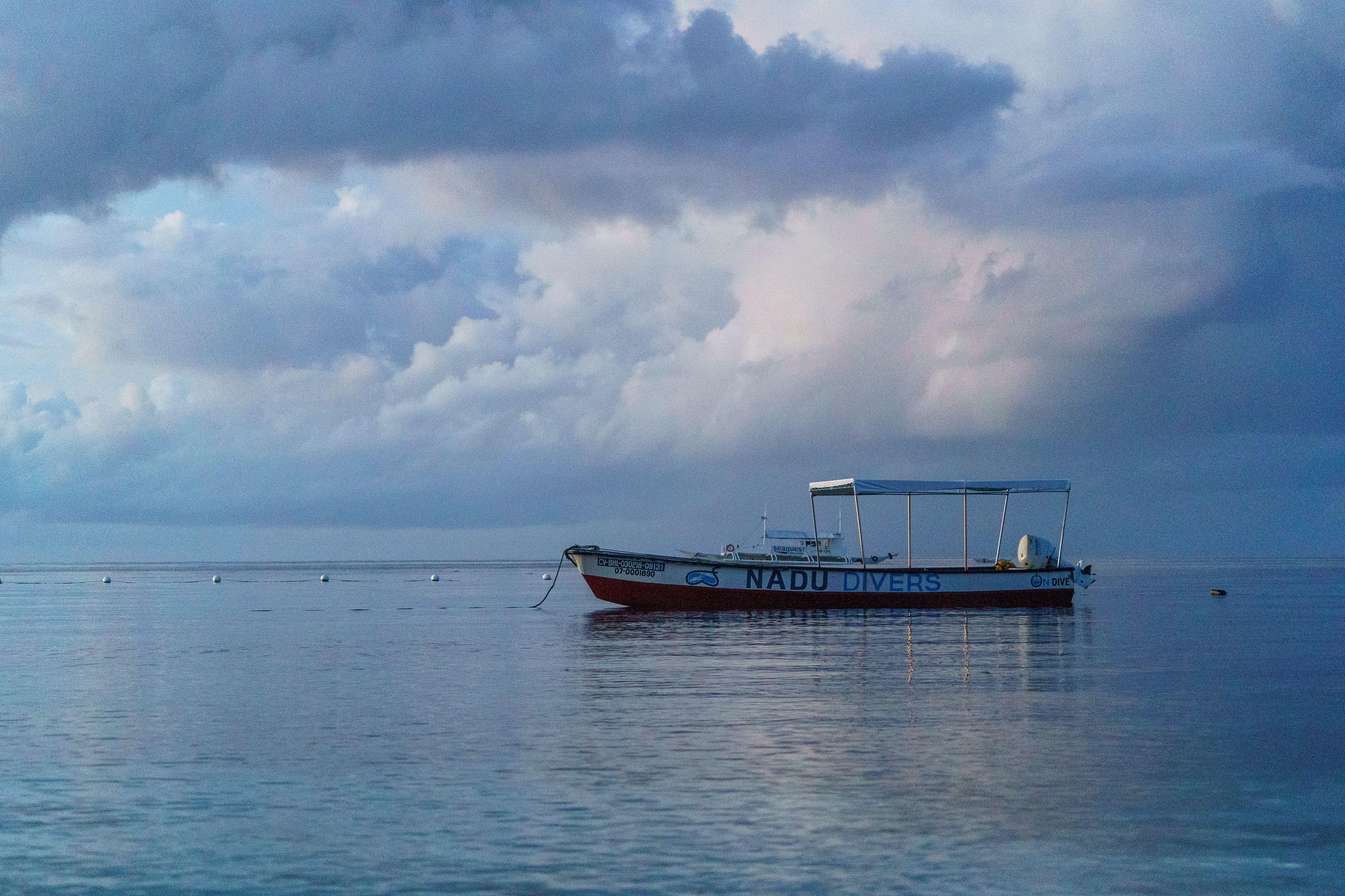 Tranquil seascape featuring a lone boat, ideal for diving enthusiasts, under an overcast sky.