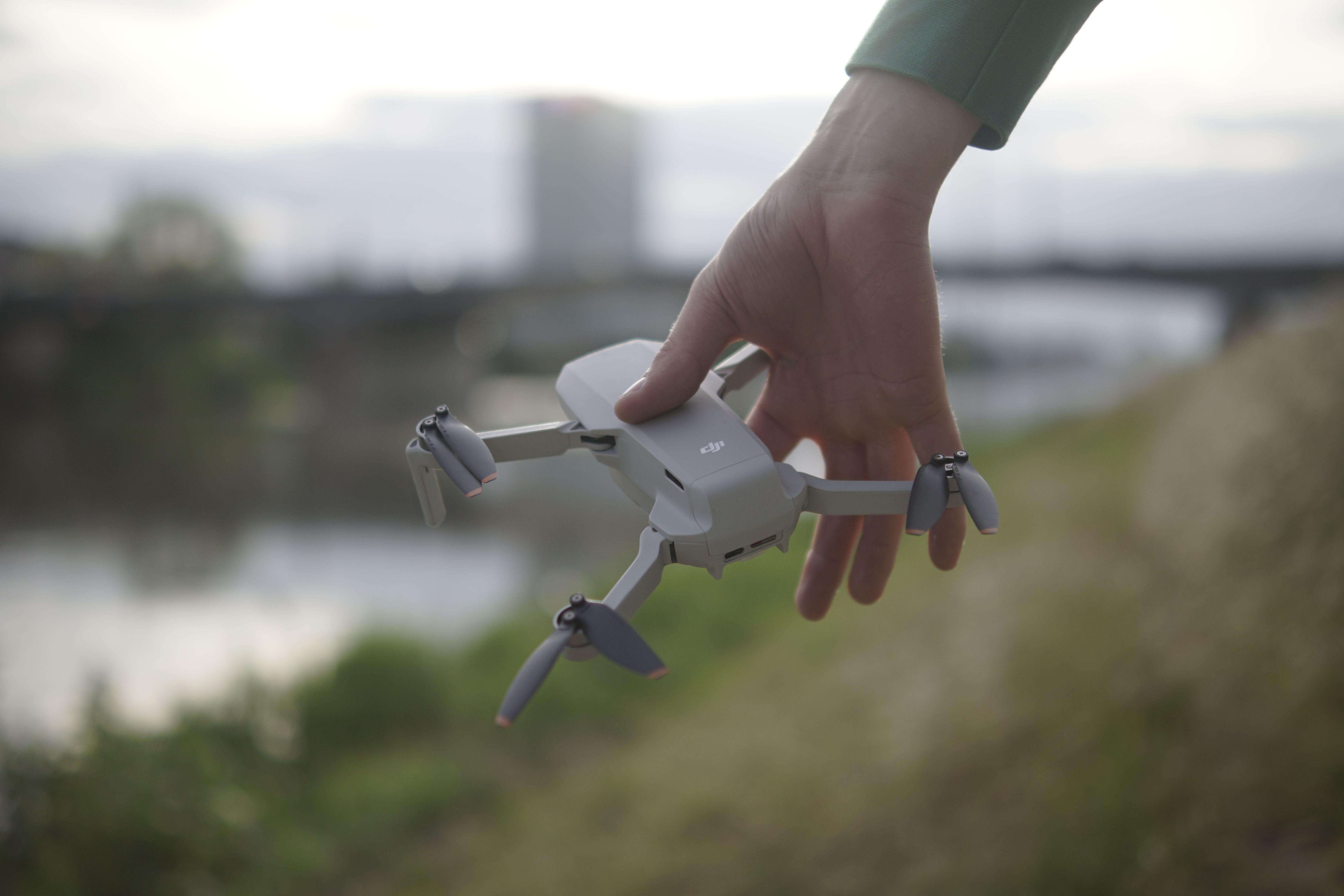 Close-up of a hand holding a small drone outdoors near a riverbank in Mannheim, Germany.