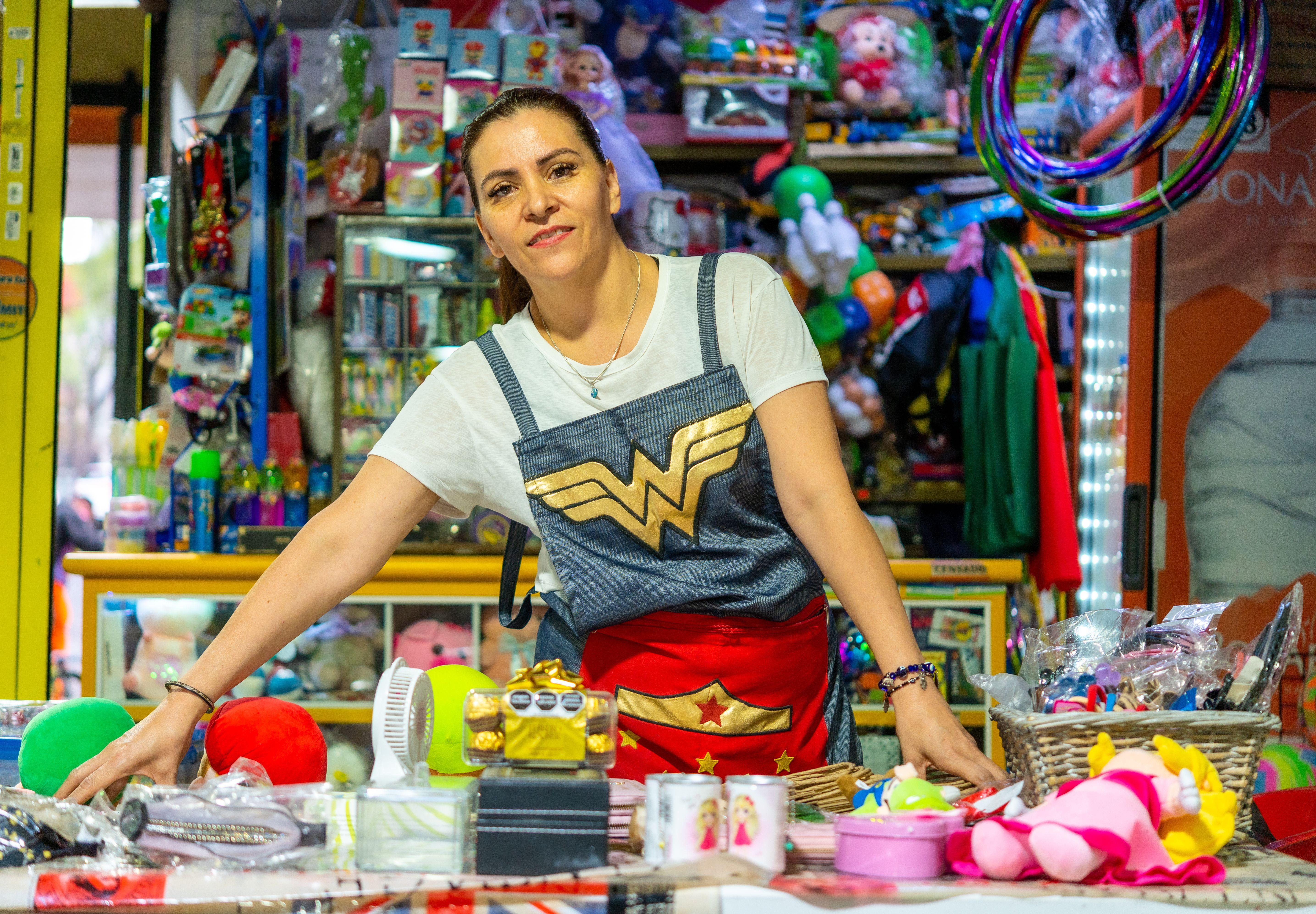 A smiling woman sells colorful toys and souvenirs at a vibrant market in Ciudad de México.