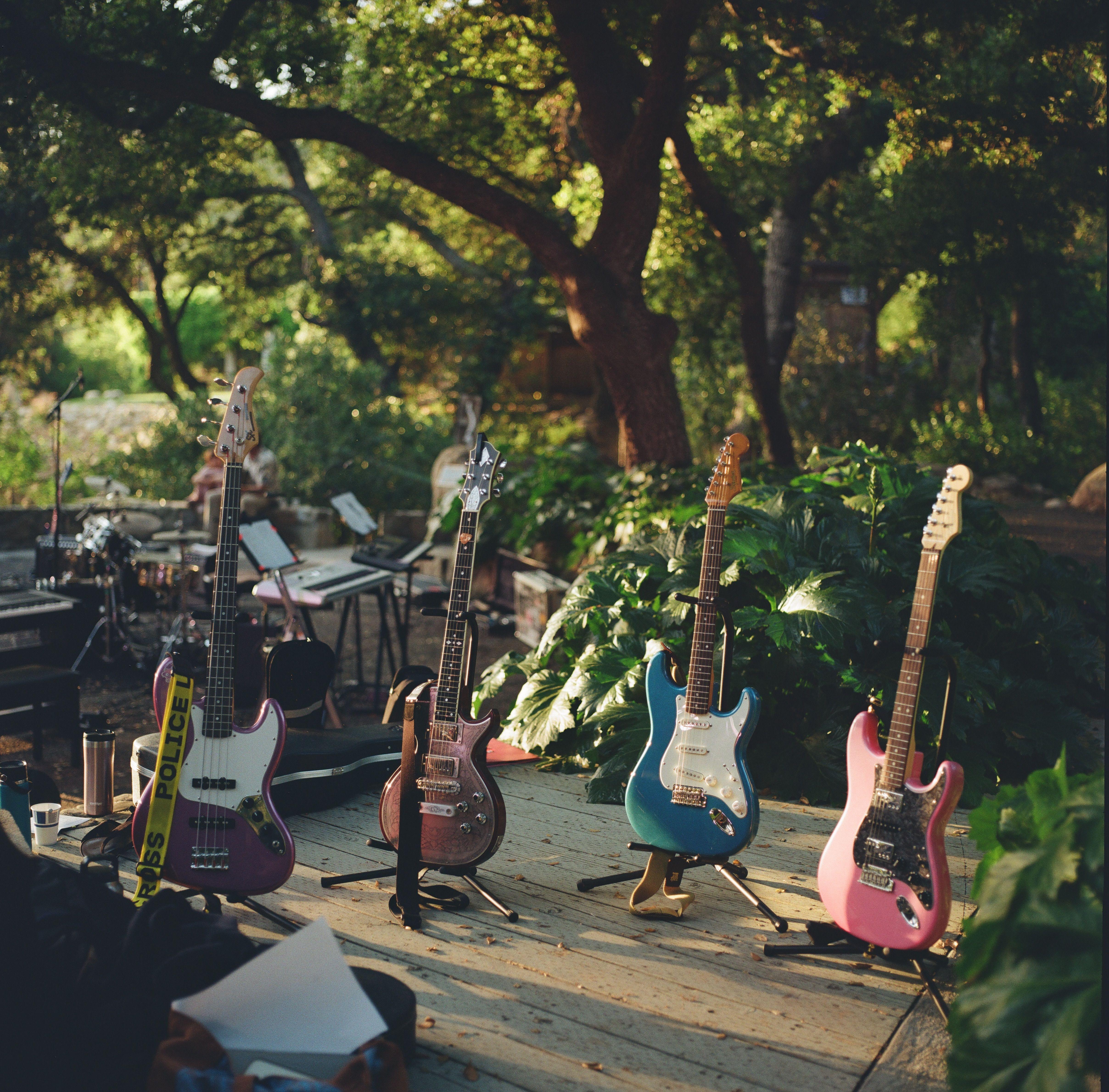 An array of colorful electric guitars set on an outdoor stage ready for a summer music festival performance.