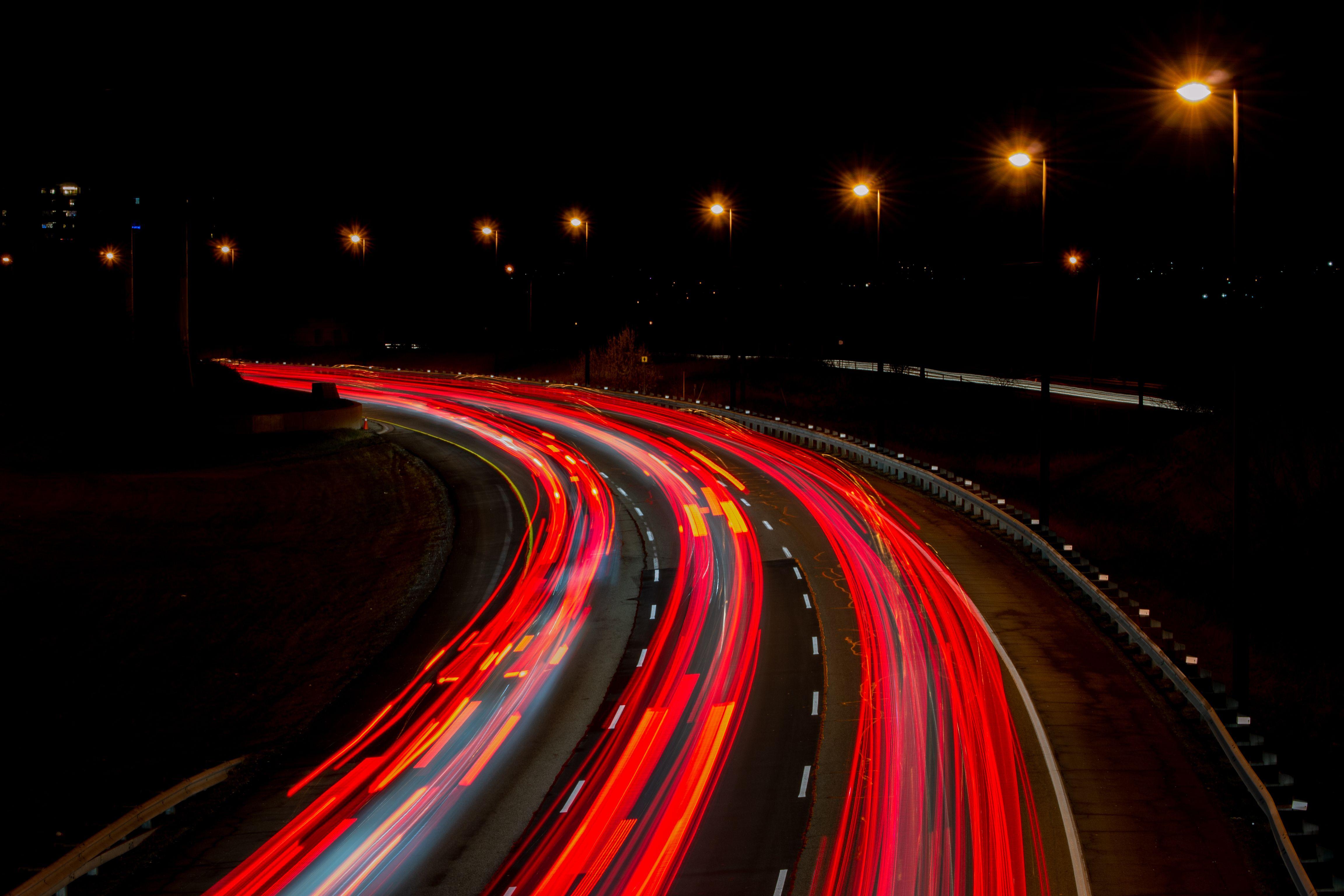 A captivating long exposure of a highway at night, showcasing vibrant light trails under streetlamps.
