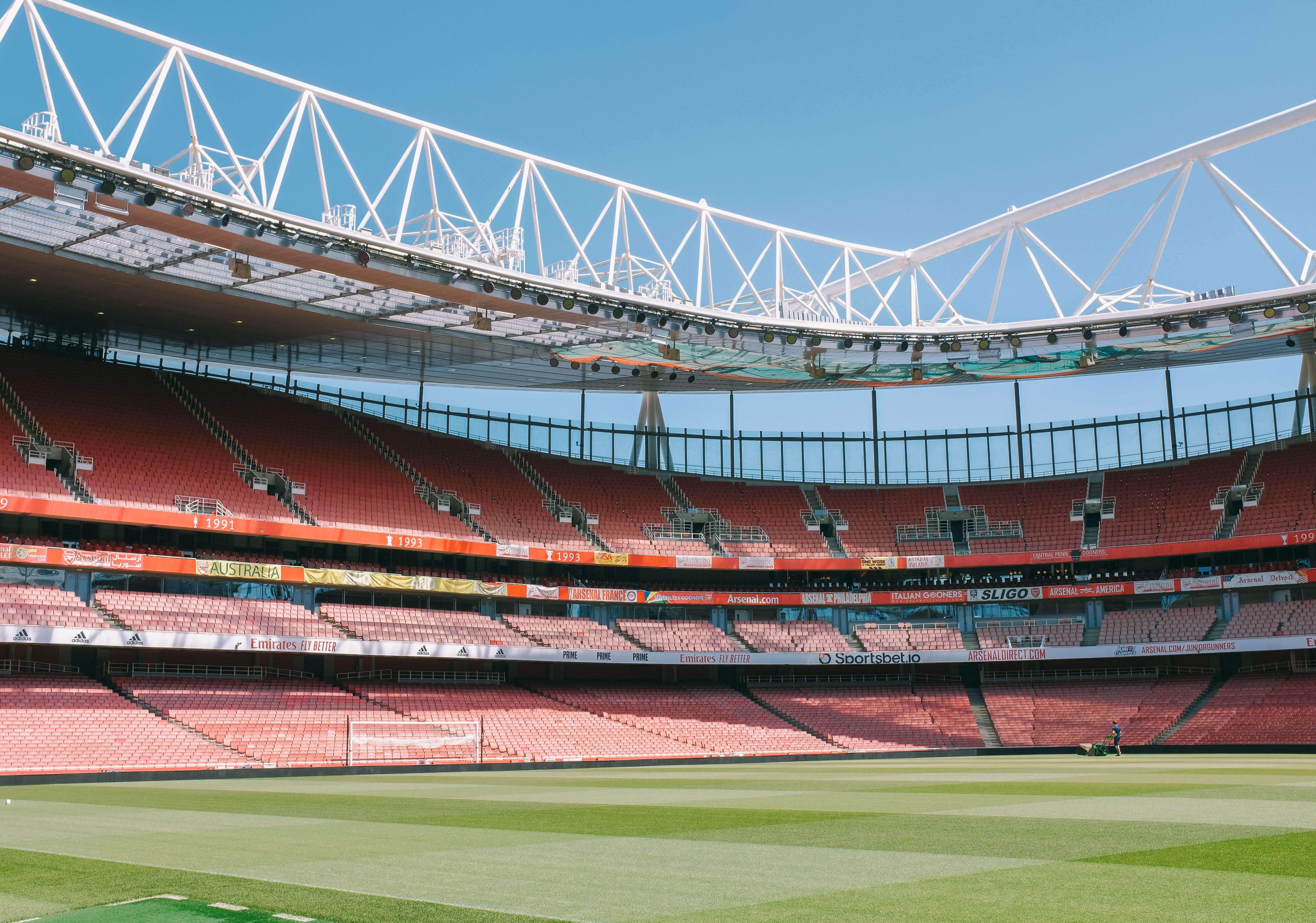 Wide view of Emirates Stadium's empty stands under a clear blue sky in London.