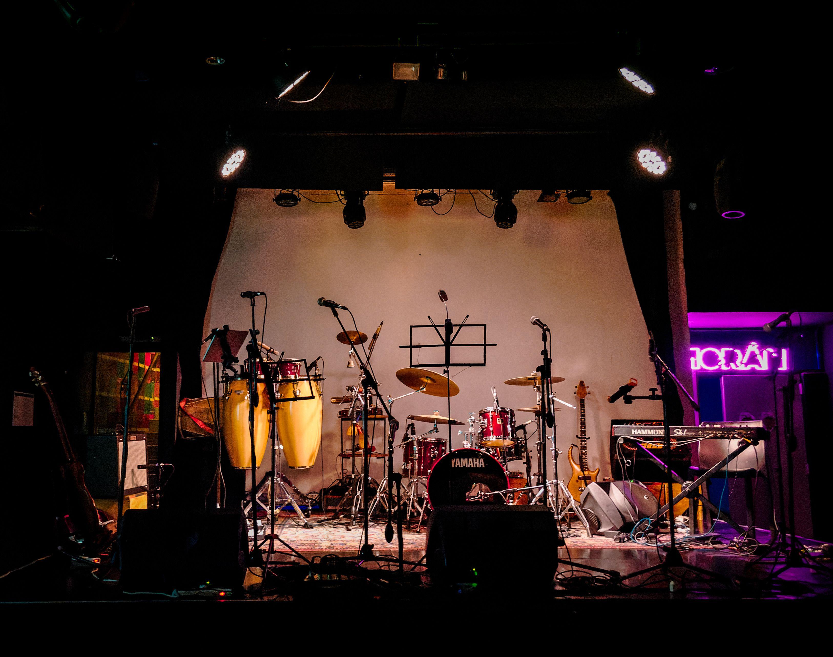 An empty stage set with musical instruments ready for a live performance in a dimly lit venue.