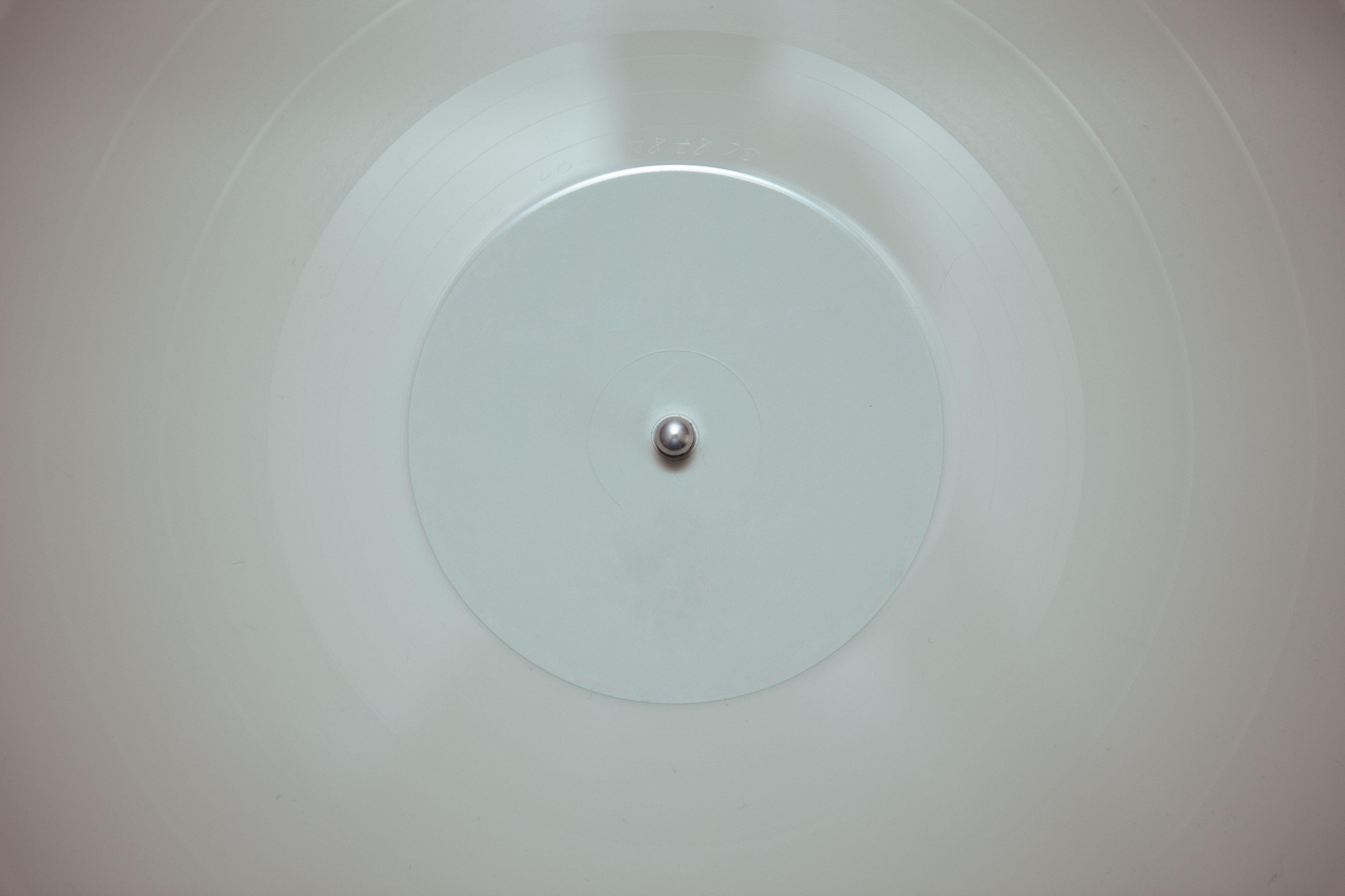 A close-up of a white vinyl record spinning on a turntable, highlighting its minimalist design.