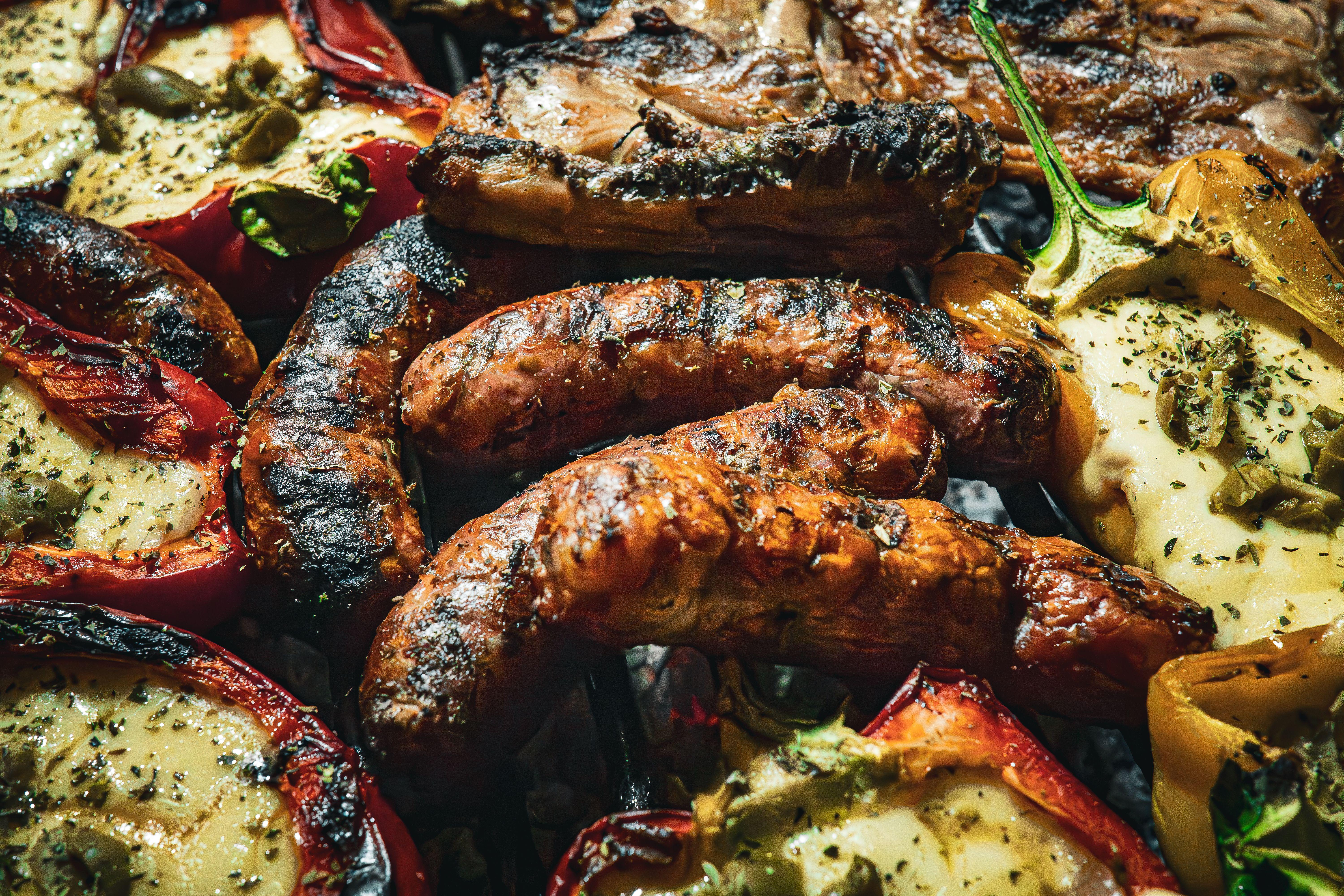 Sizzling grilled meats and stuffed peppers on a barbecue, capturing the essence of summer dining.