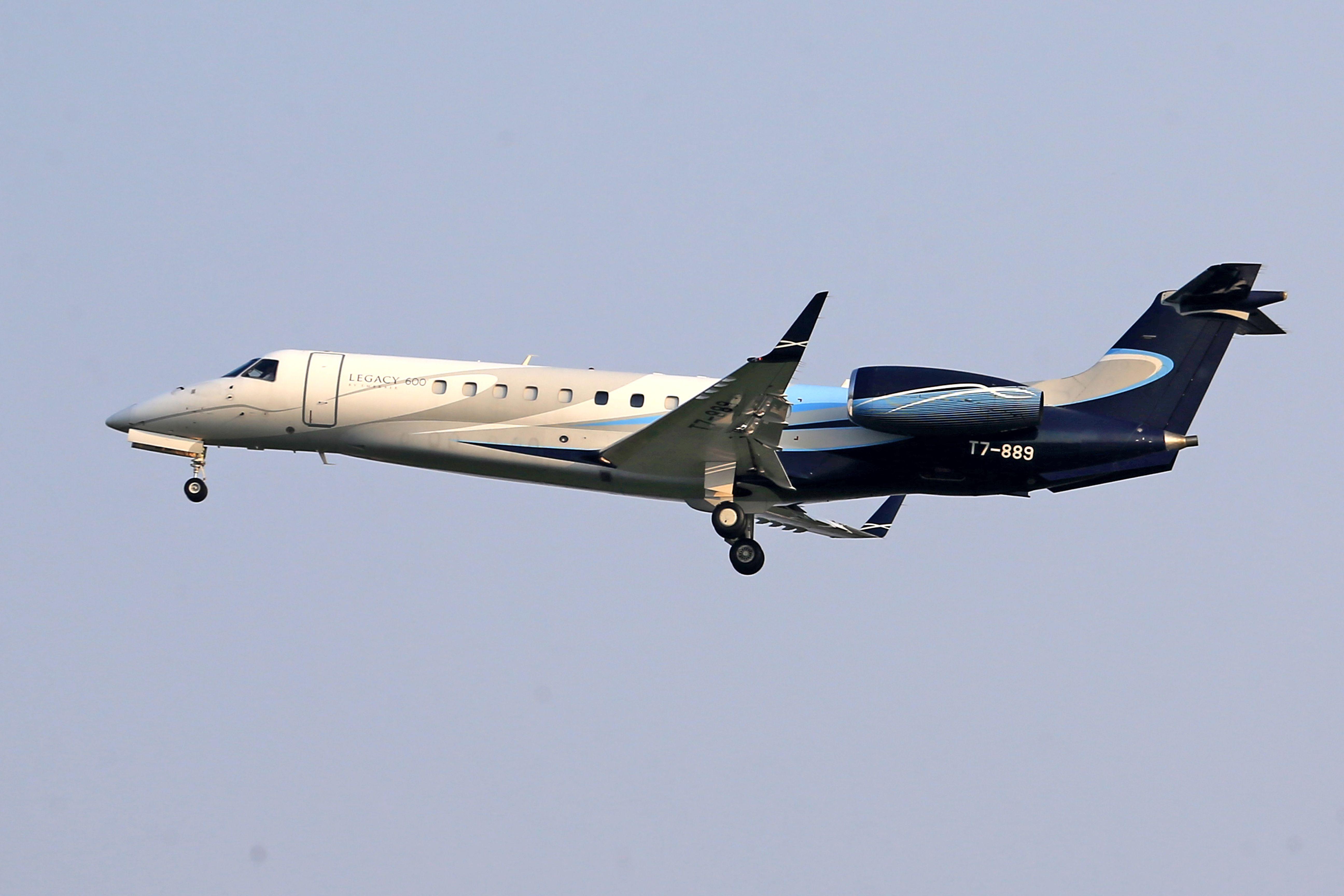 Embraer Legacy 600 private jet flying in clear blue sky, showcasing sleek design and elegance.