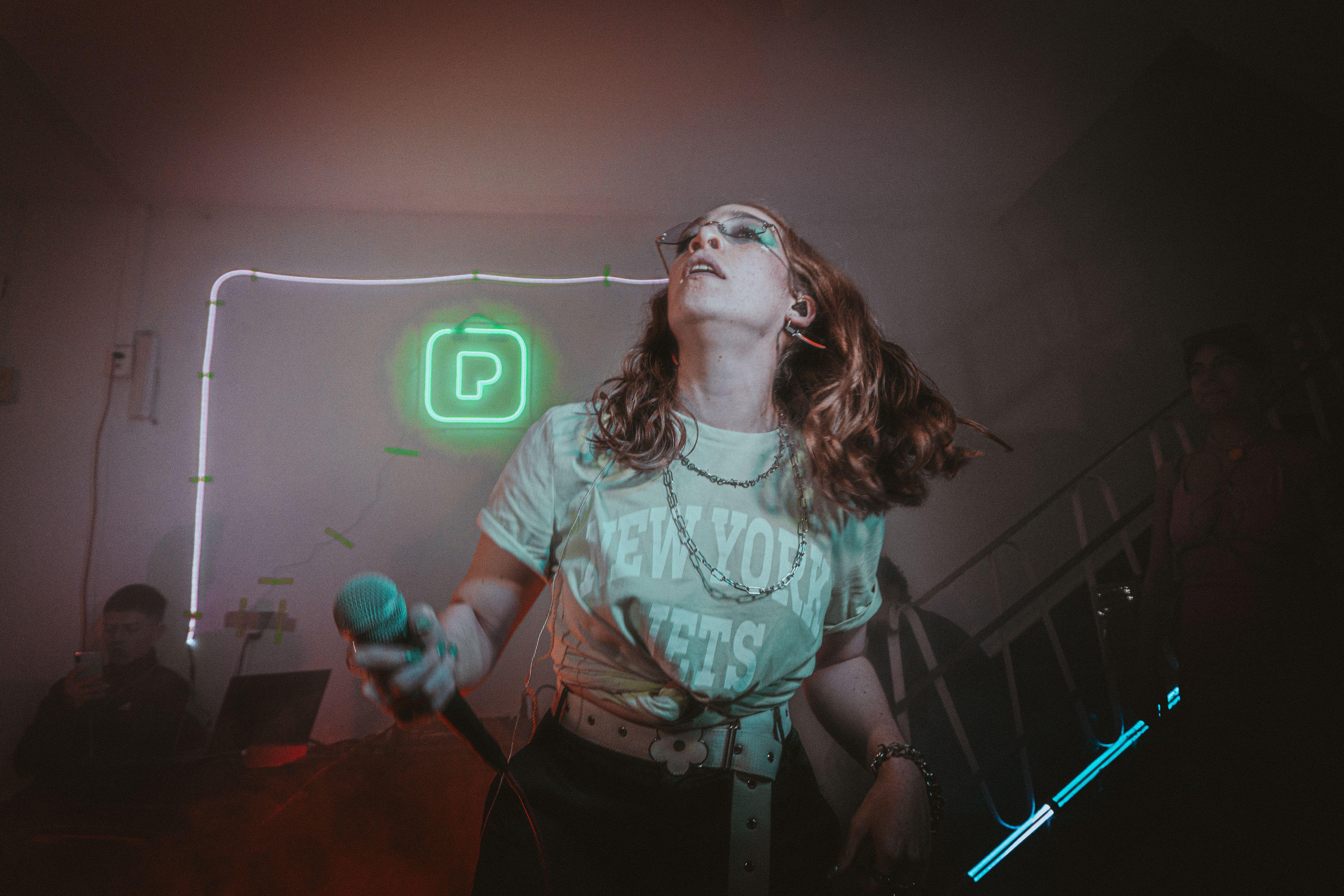 Singer performing with dynamic energy at a neon-lit indoor concert stage.