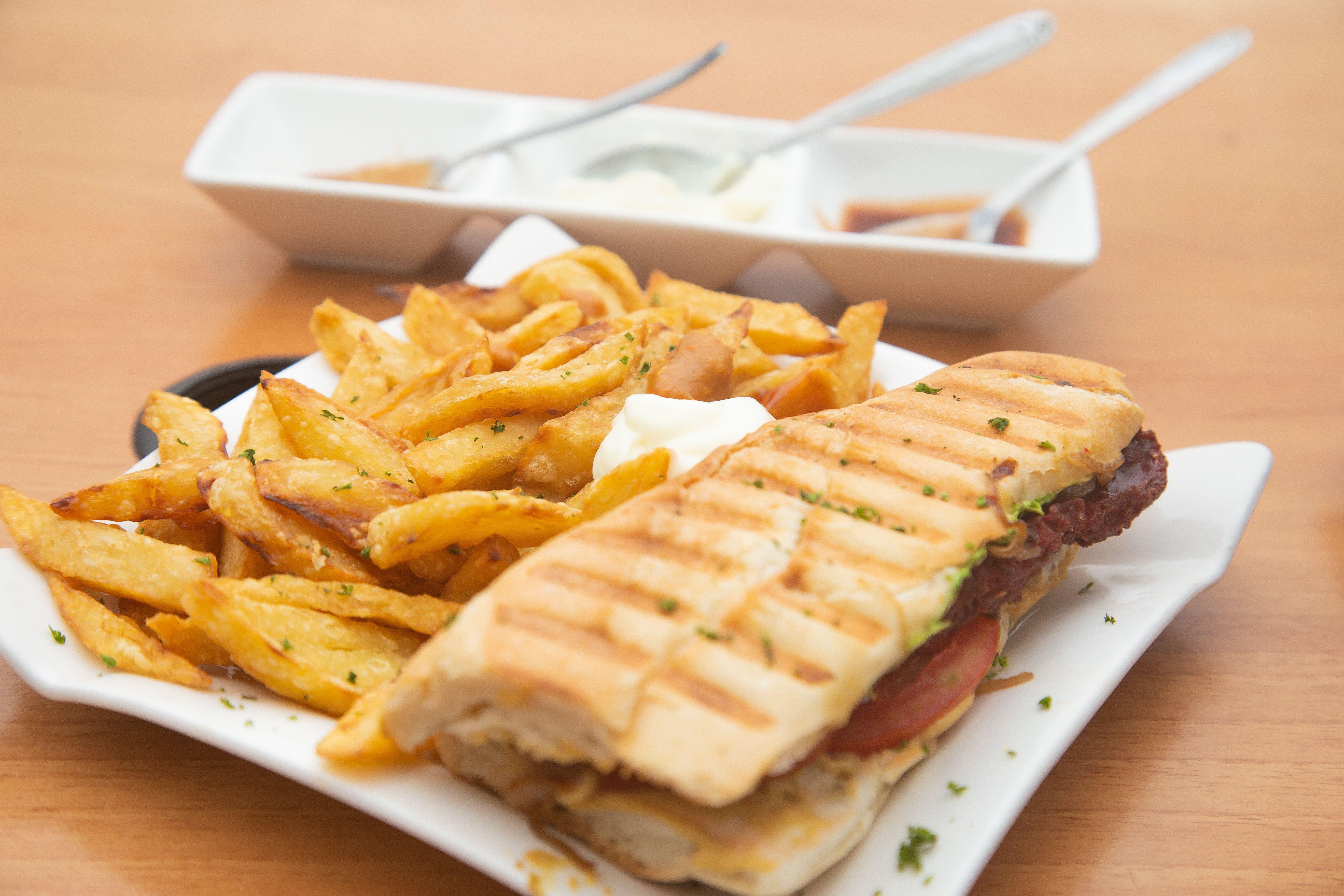 Tasty grilled sandwich served with golden fries and sauces.