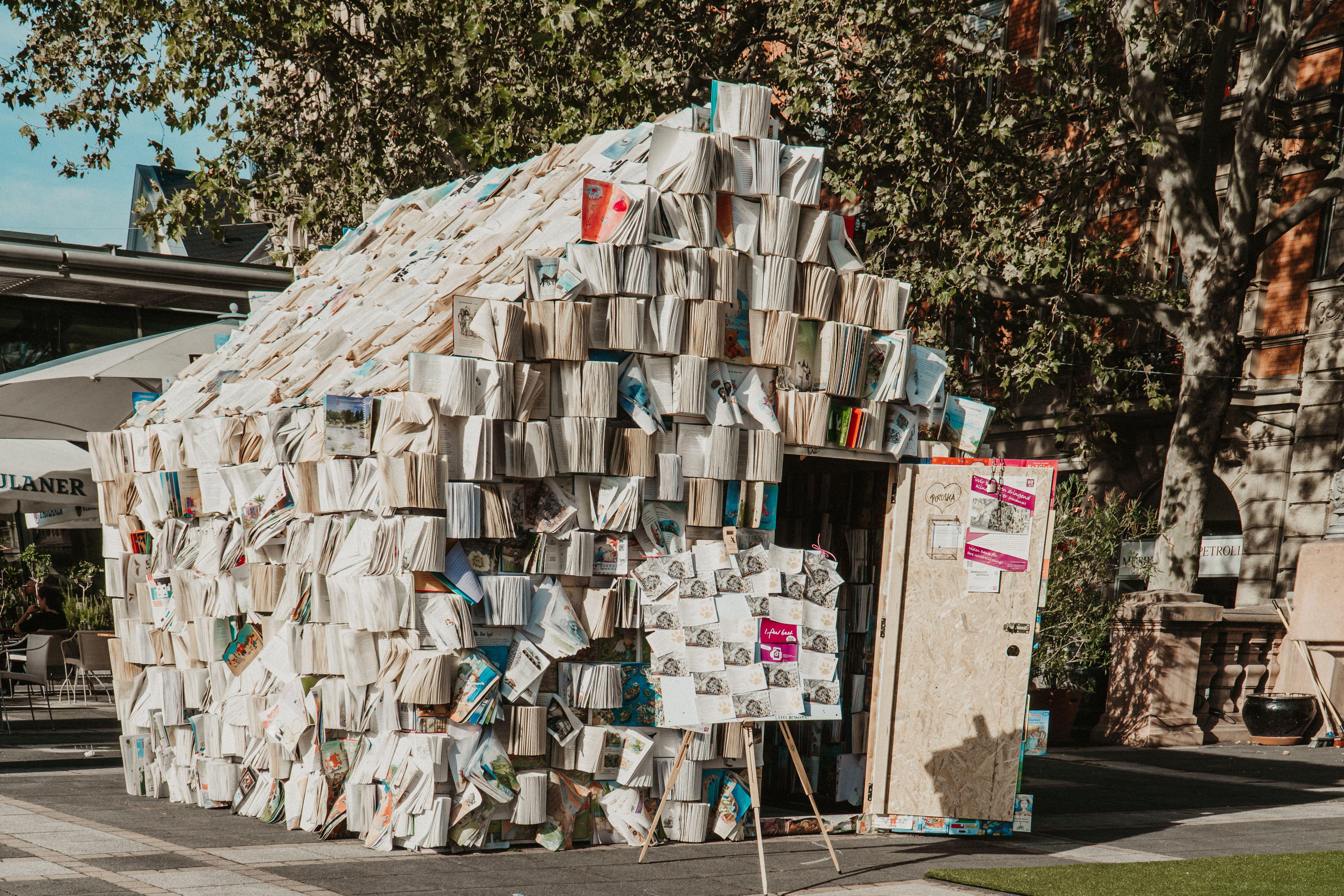 Unique architectural structure made entirely of books, showcasing creativity and literature in an urban outdoor location.