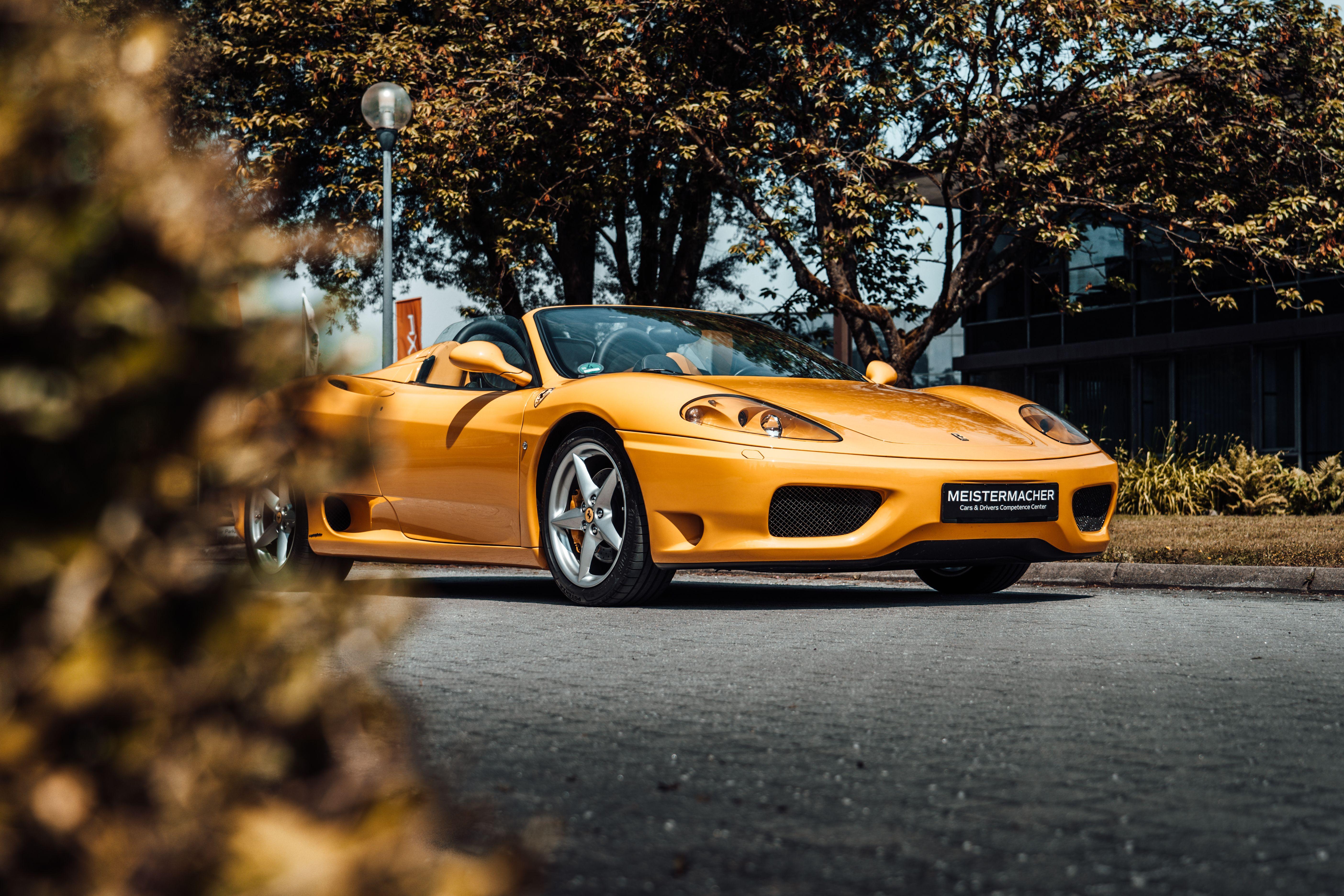 A striking yellow convertible car parked on a scenic city street during autumn.