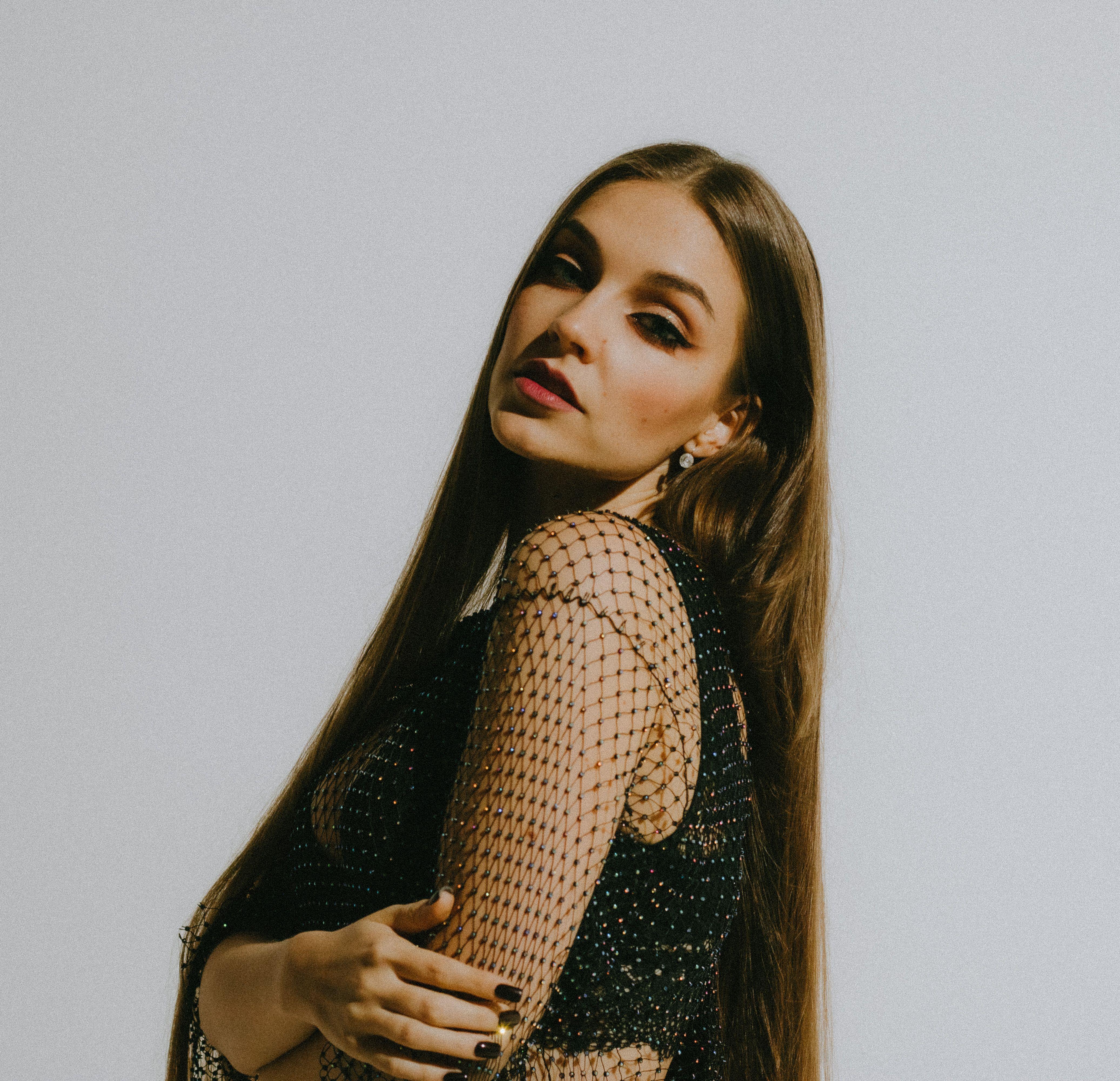 Studio portrait of a woman in stylish attire with long hair, exuding elegance and confidence.