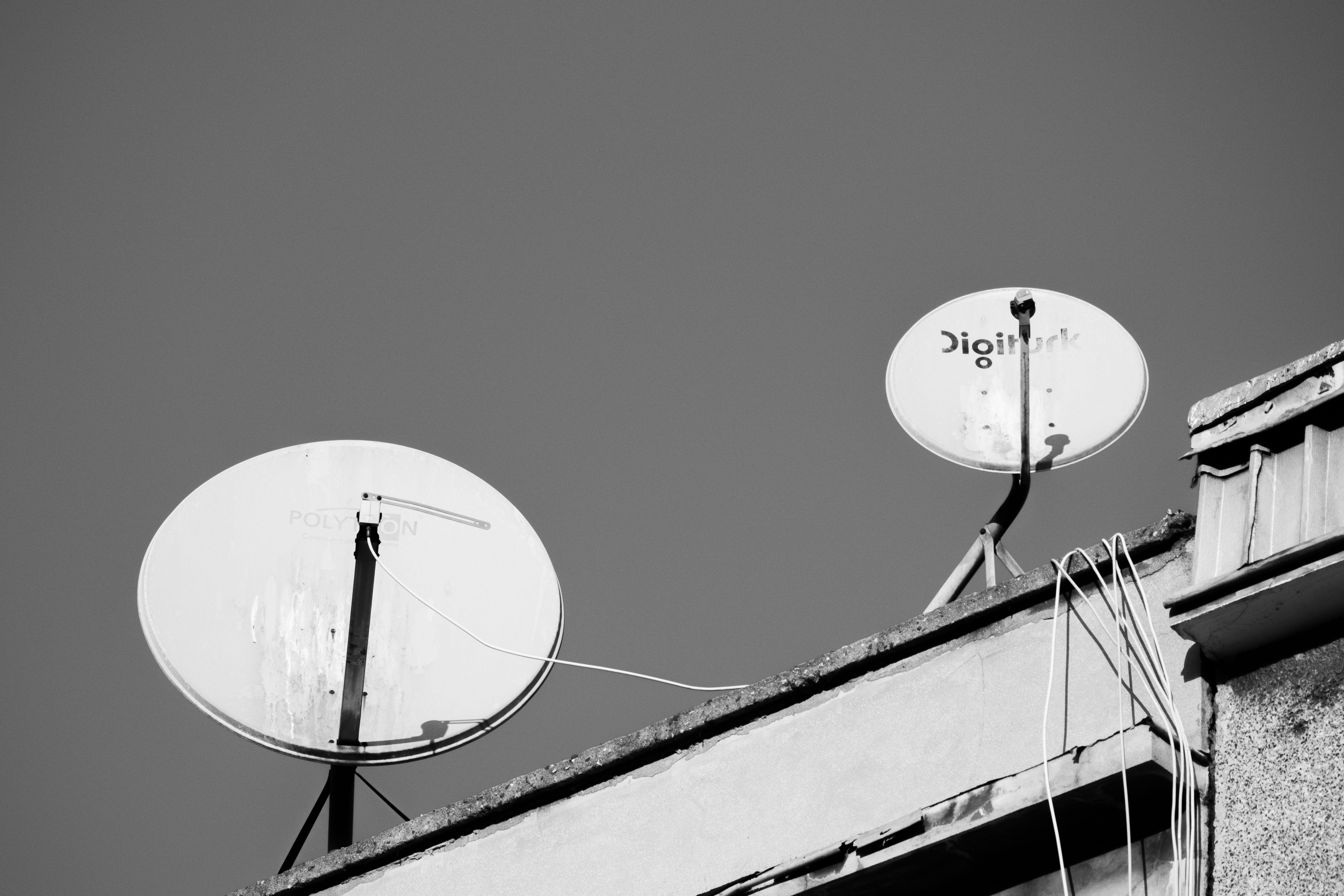 Monochrome image of two satellite dishes on a rooftop, representing communication technology.