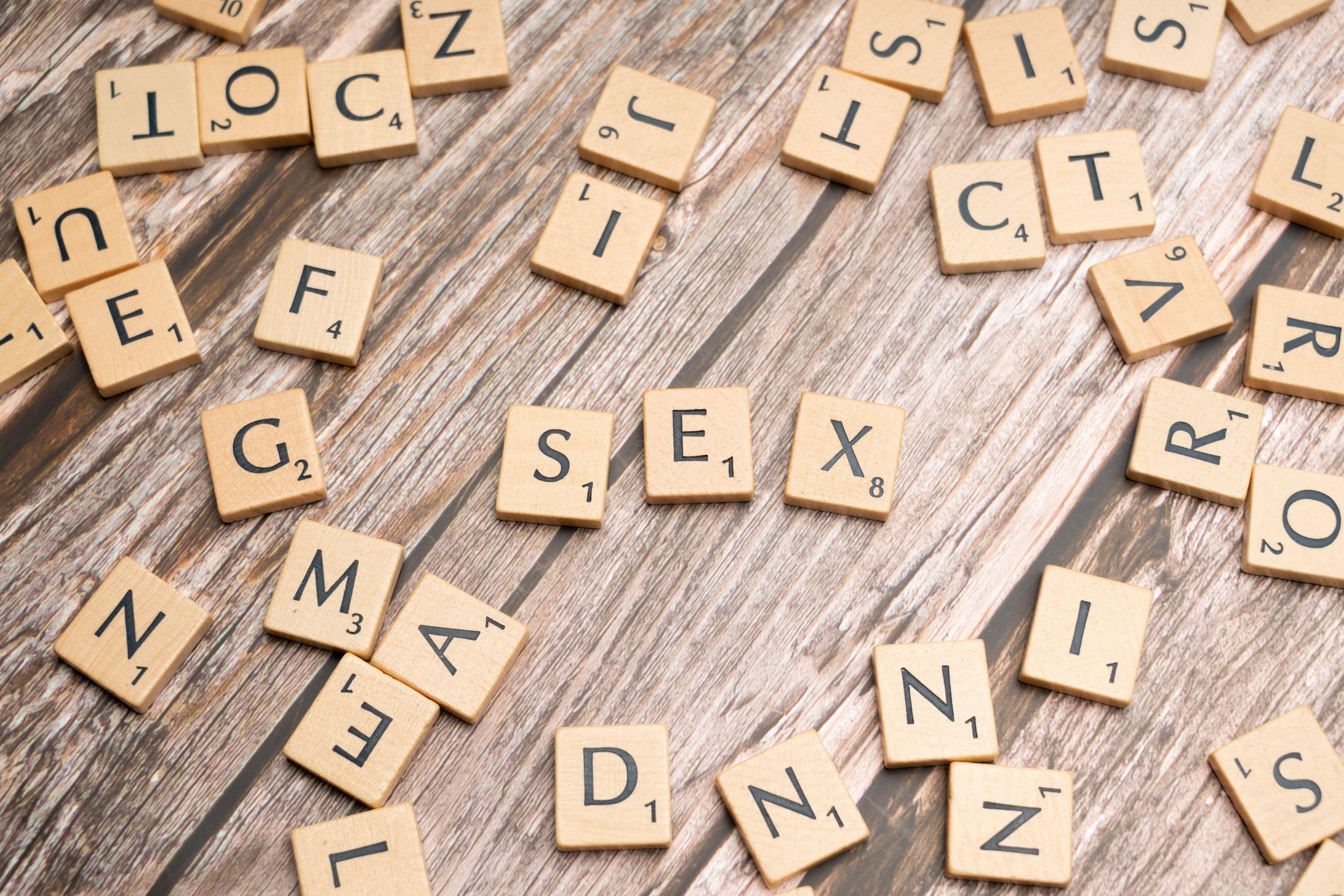 Scattered wooden letter tiles on a wooden surface, forming words.