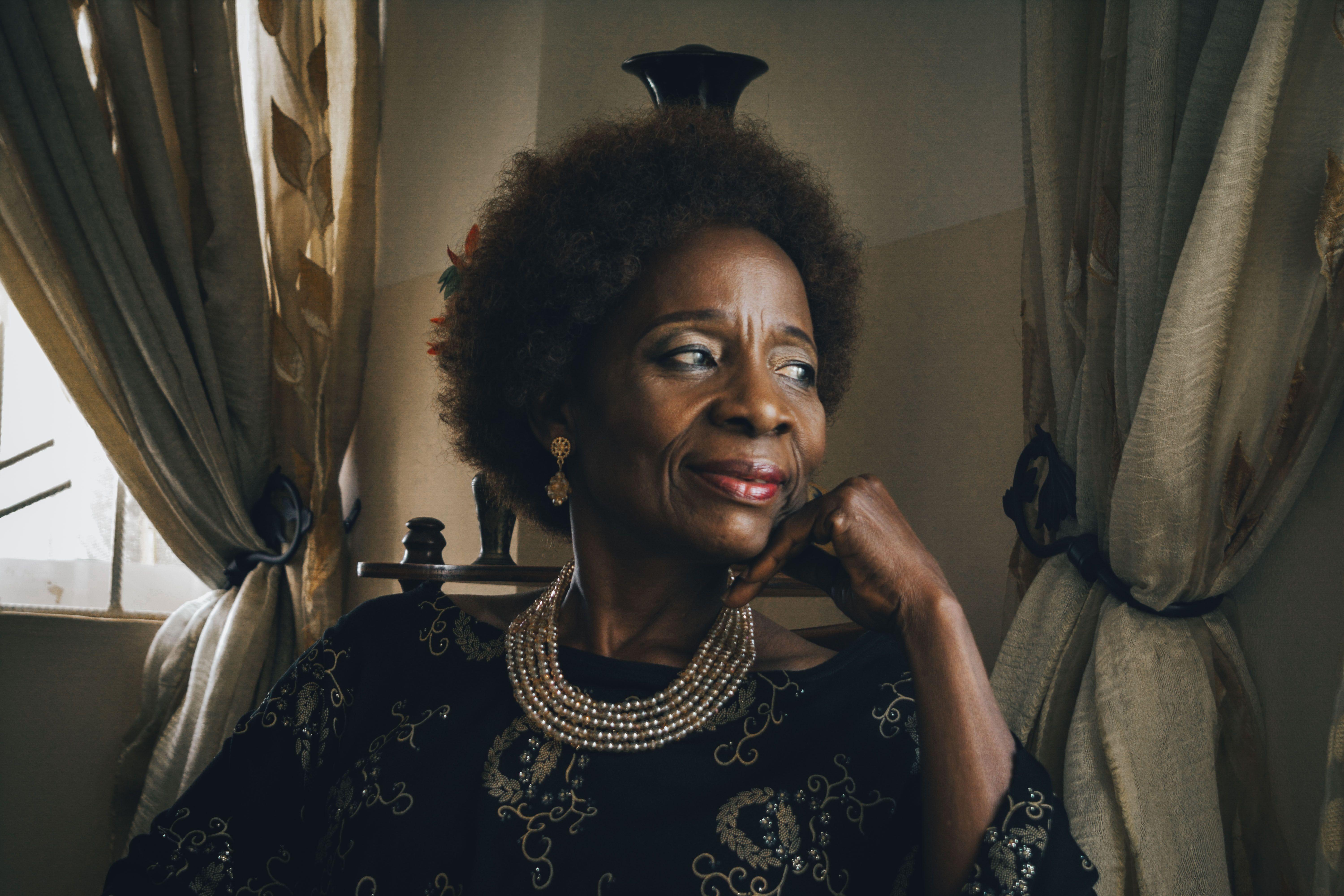 Portrait of an older woman with curly hair and jewelry, reflecting elegance and wisdom.