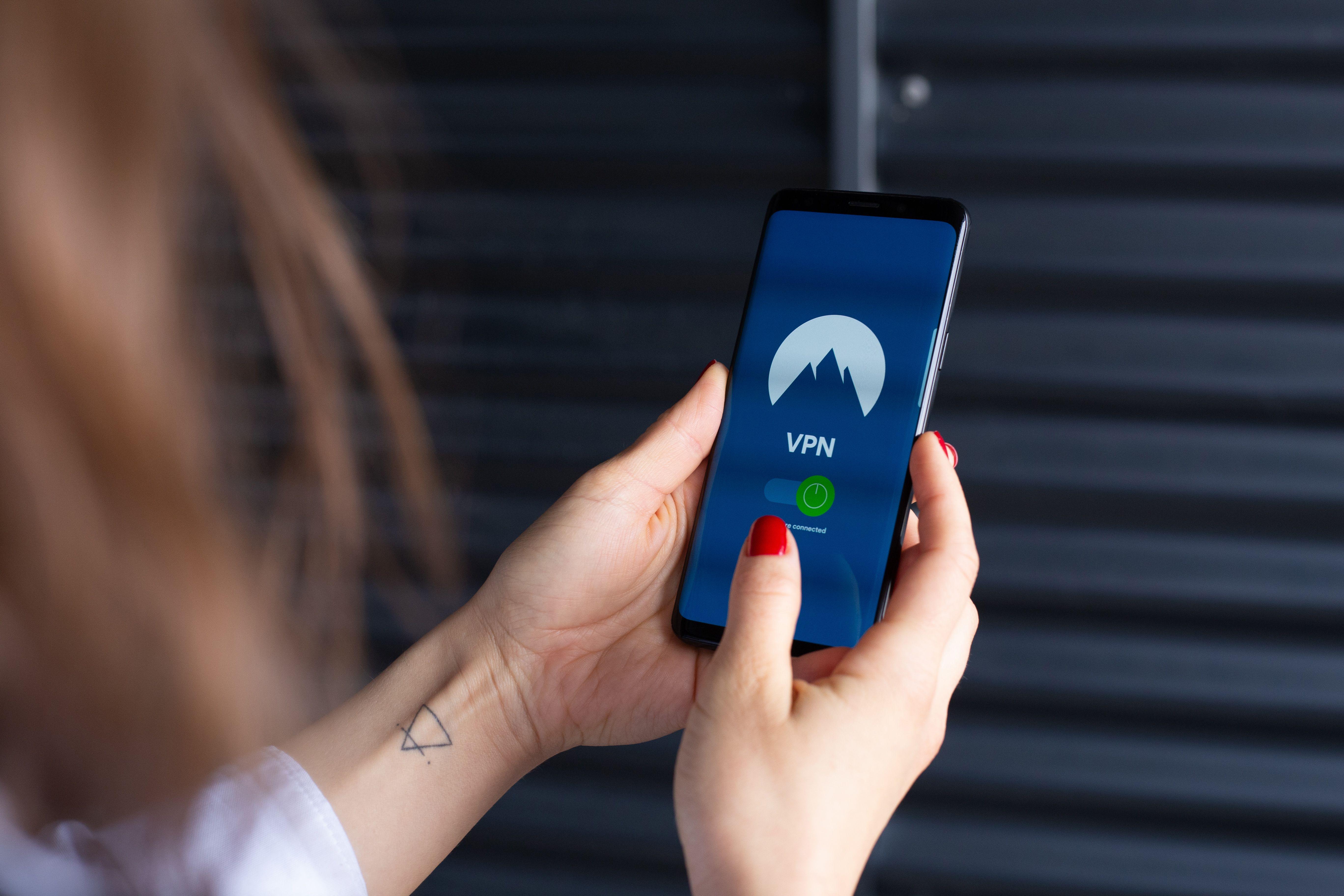 Close-up of a woman's hands using a VPN app on a smartphone, emphasizing digital security.