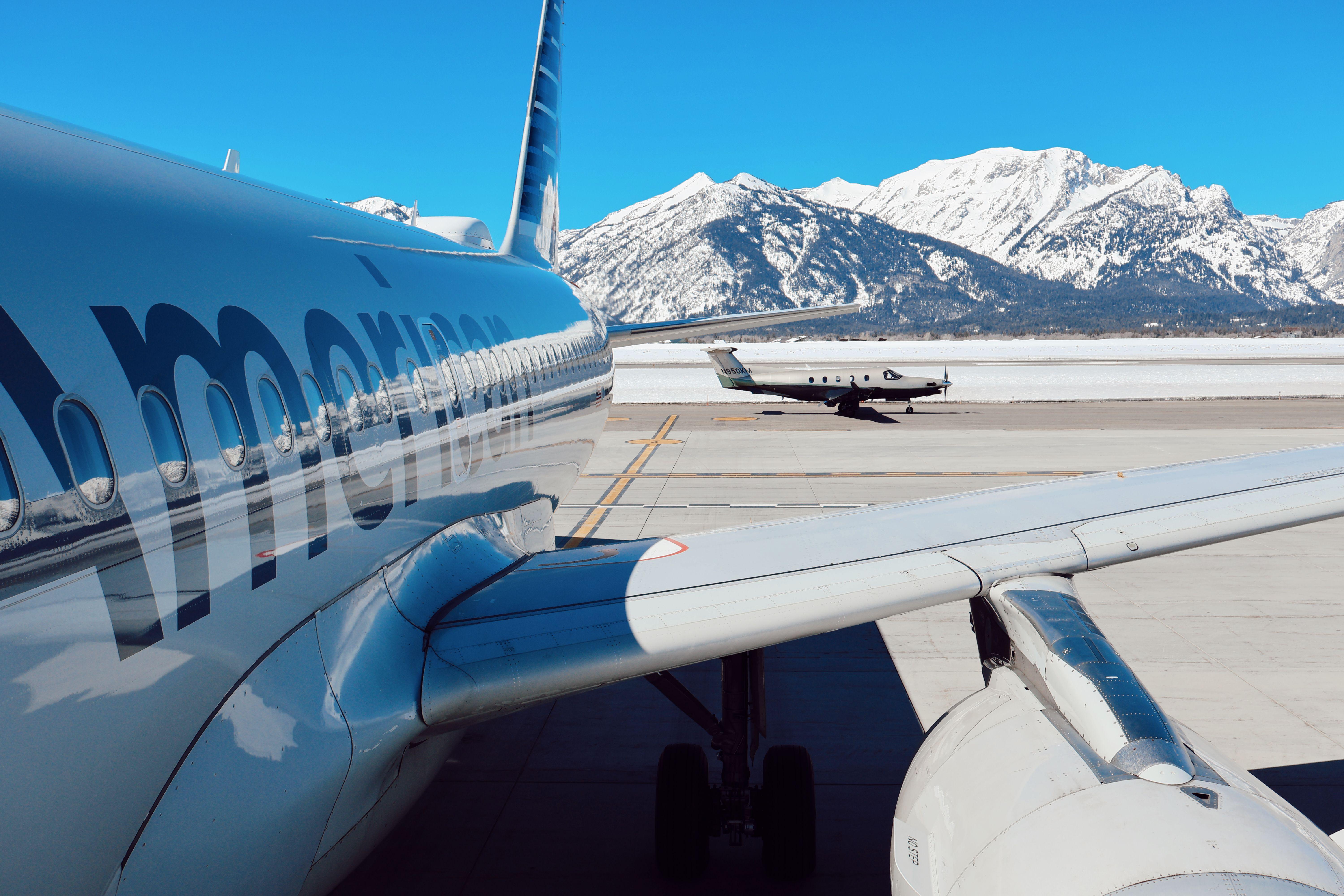 Airplanes parked at Jackson Hole Airport with snowy Teton mountains in the background.