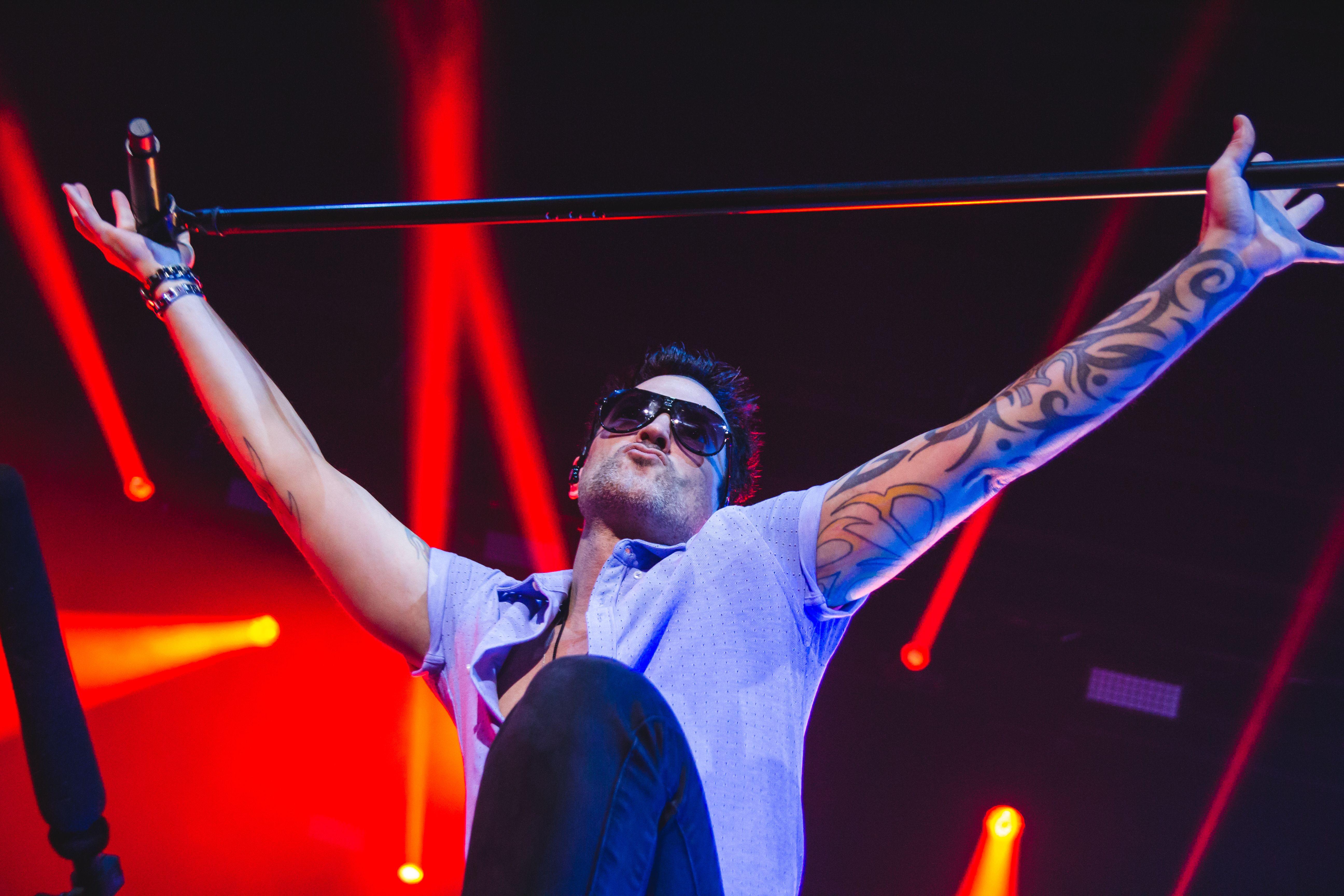 Exciting concert moment with a performer holding a microphone stand amidst bright stage lights.