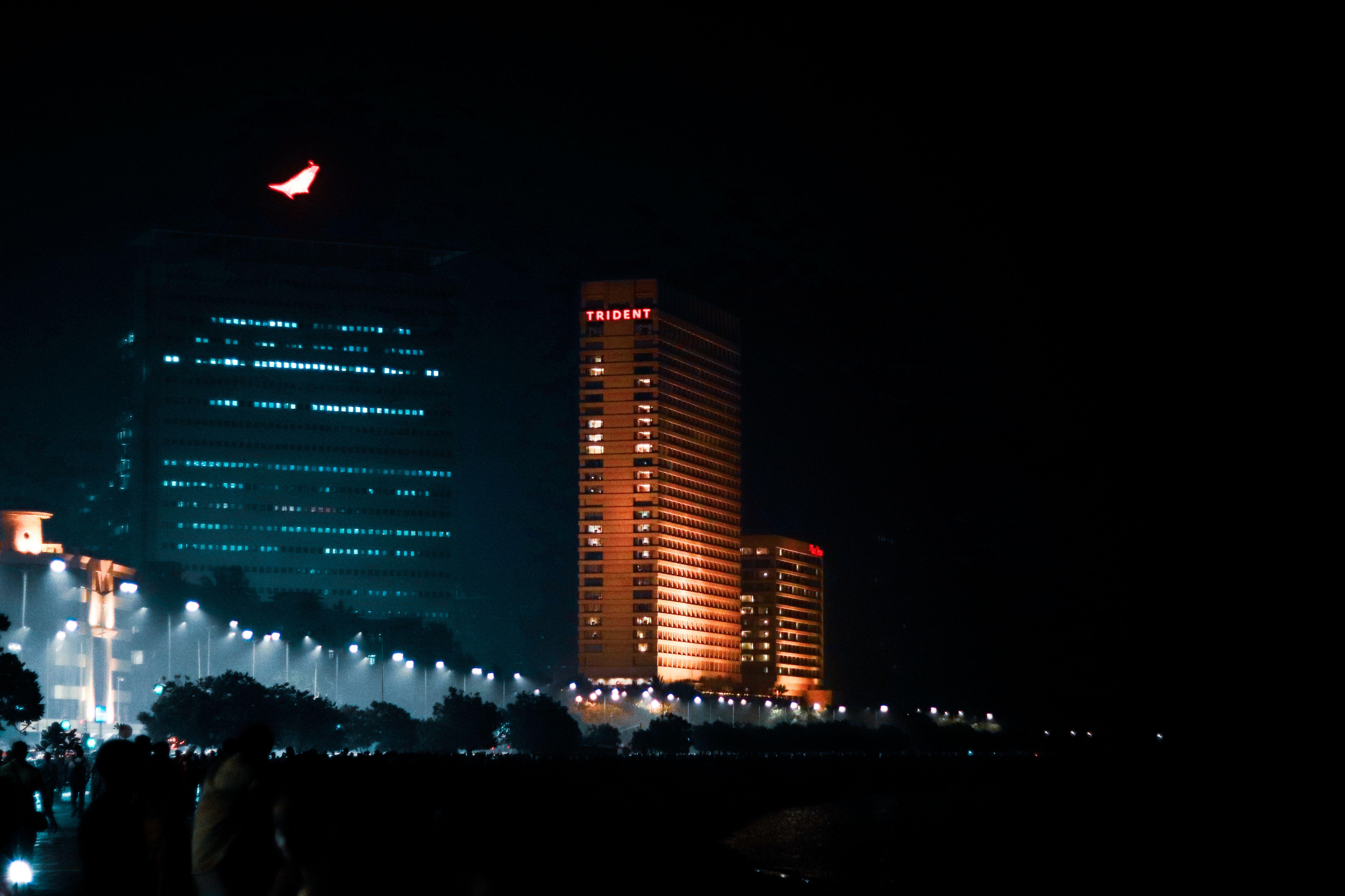 Nighttime view of the illuminated Trident Hotel in Mumbai, showcasing vibrant city lights.