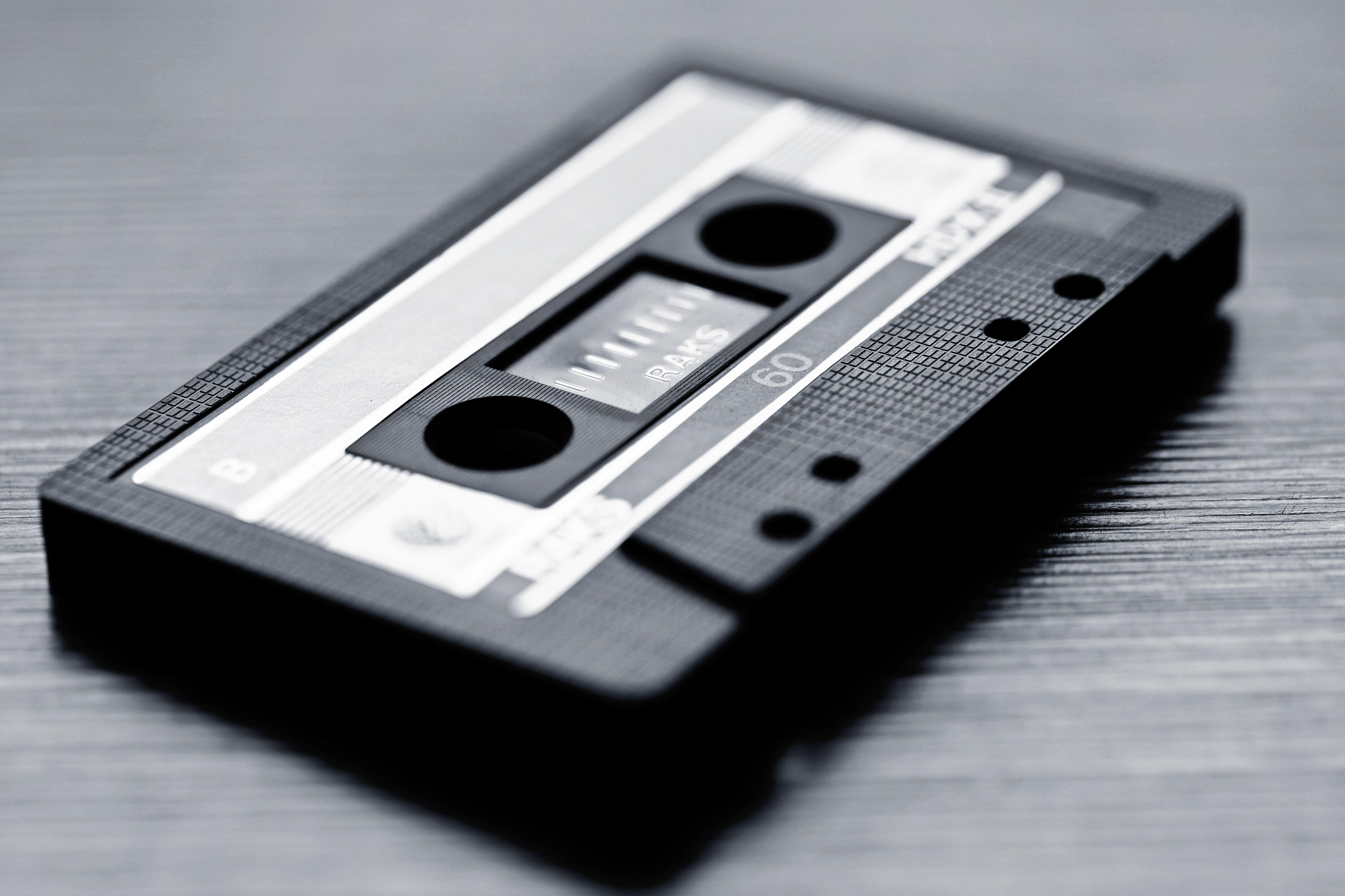 Close-up of a vintage cassette tape on wooden surface in black and white.