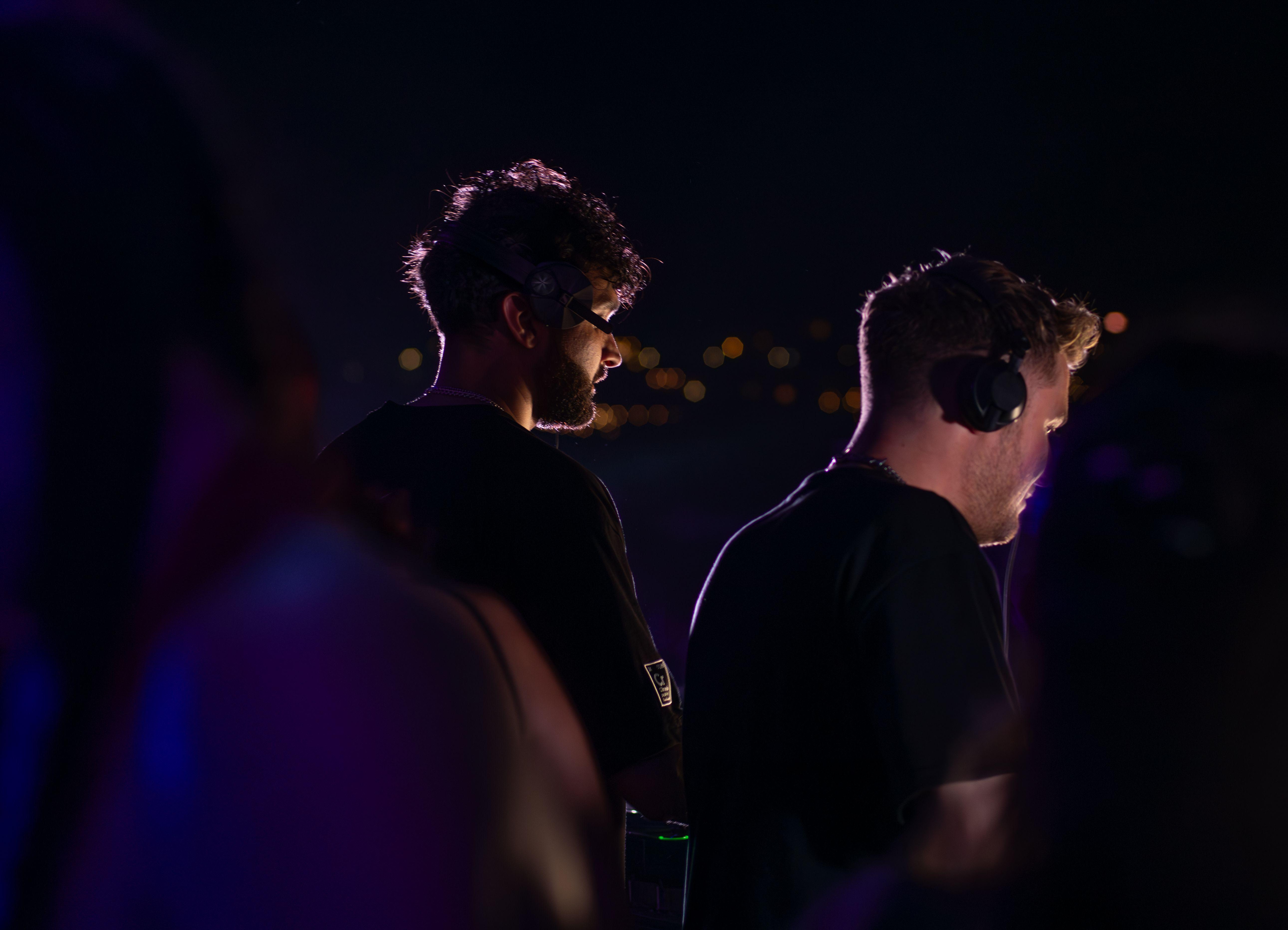 Two DJs wearing headphones performing at a nighttime event in Sozopol, Bulgaria.