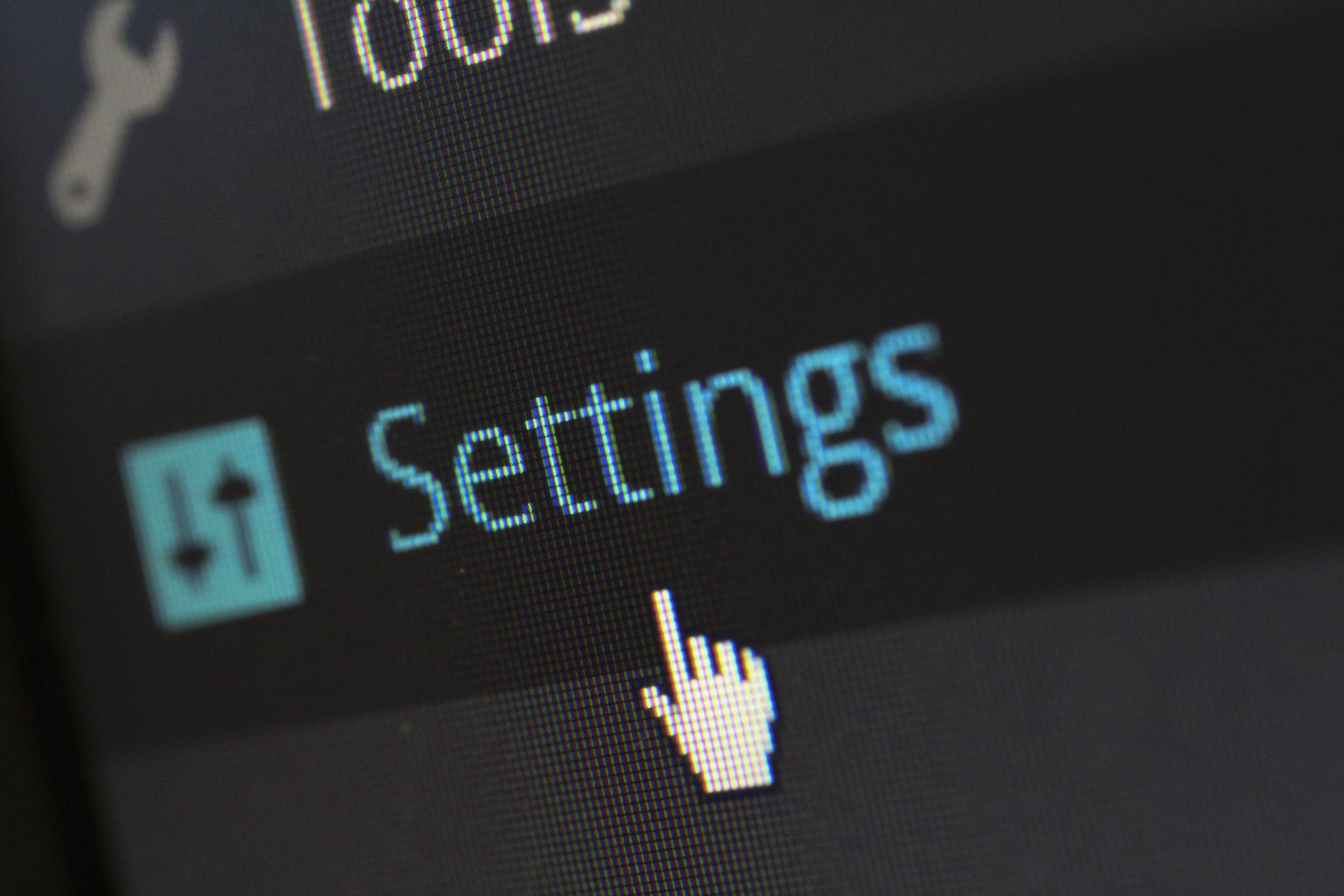 A close-up photo of a computer screen showing the settings button with a cursor hovering over it.
