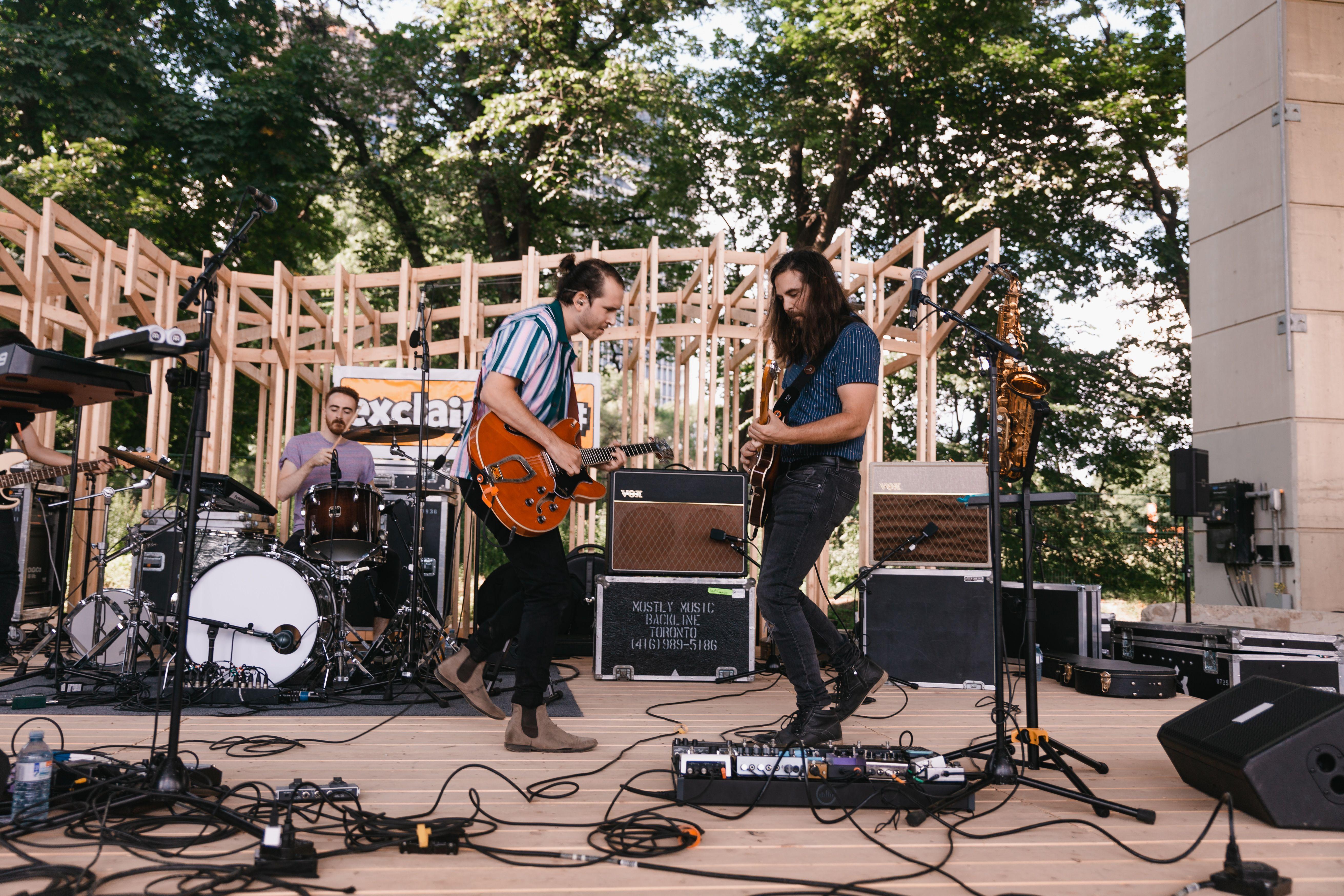 Live band playing on an outdoor stage with drums and electric guitars. Captivating performance.