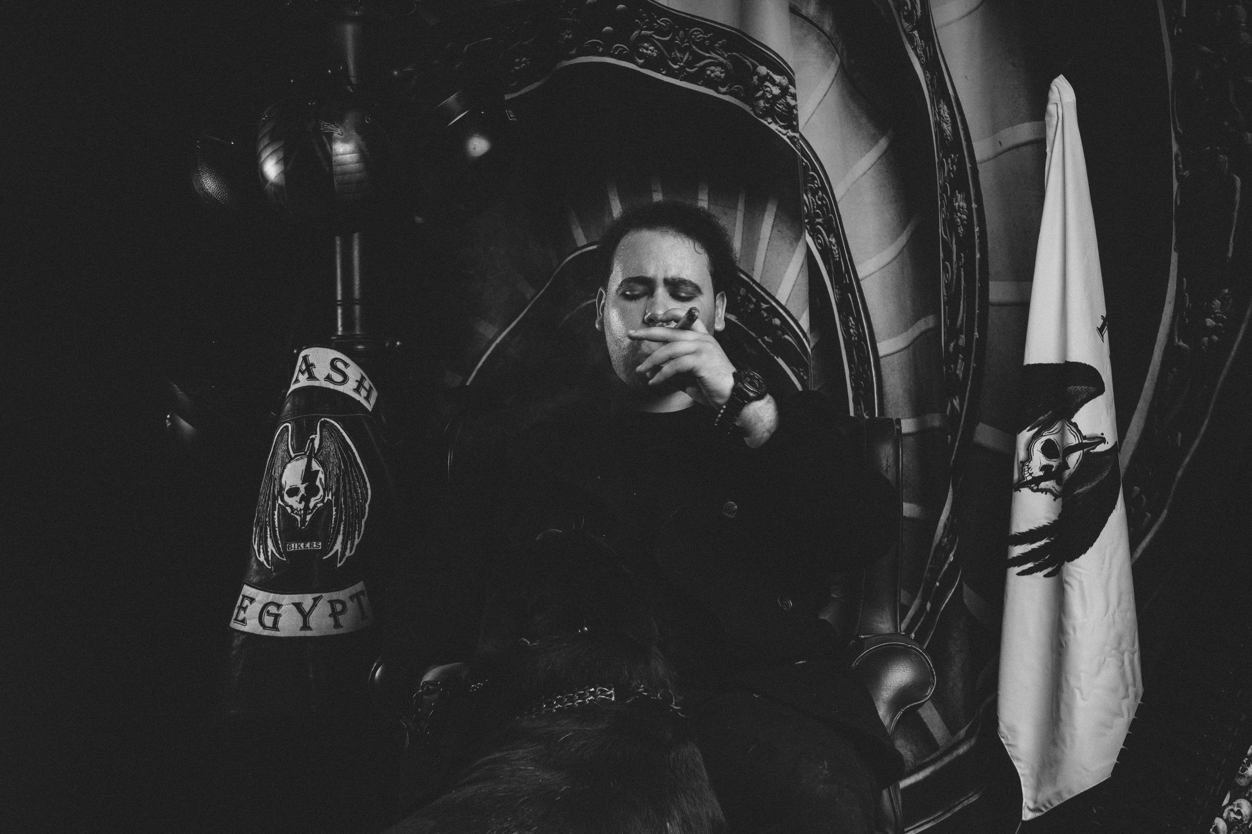 Black and white portrait of a man smoking indoors with a dramatic atmosphere.