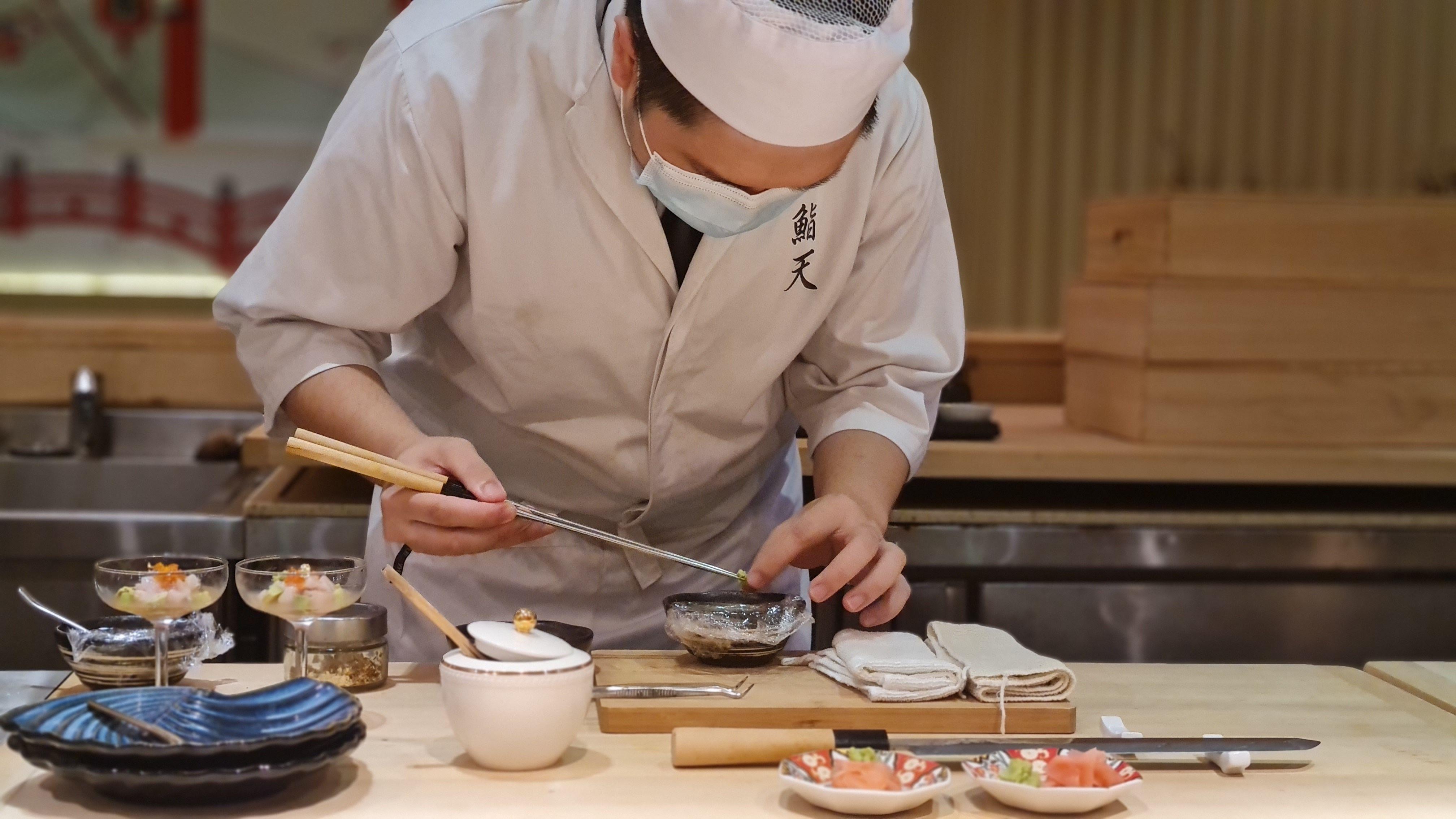 A skilled Japanese chef meticulously prepares sashimi in an intimate restaurant setting.