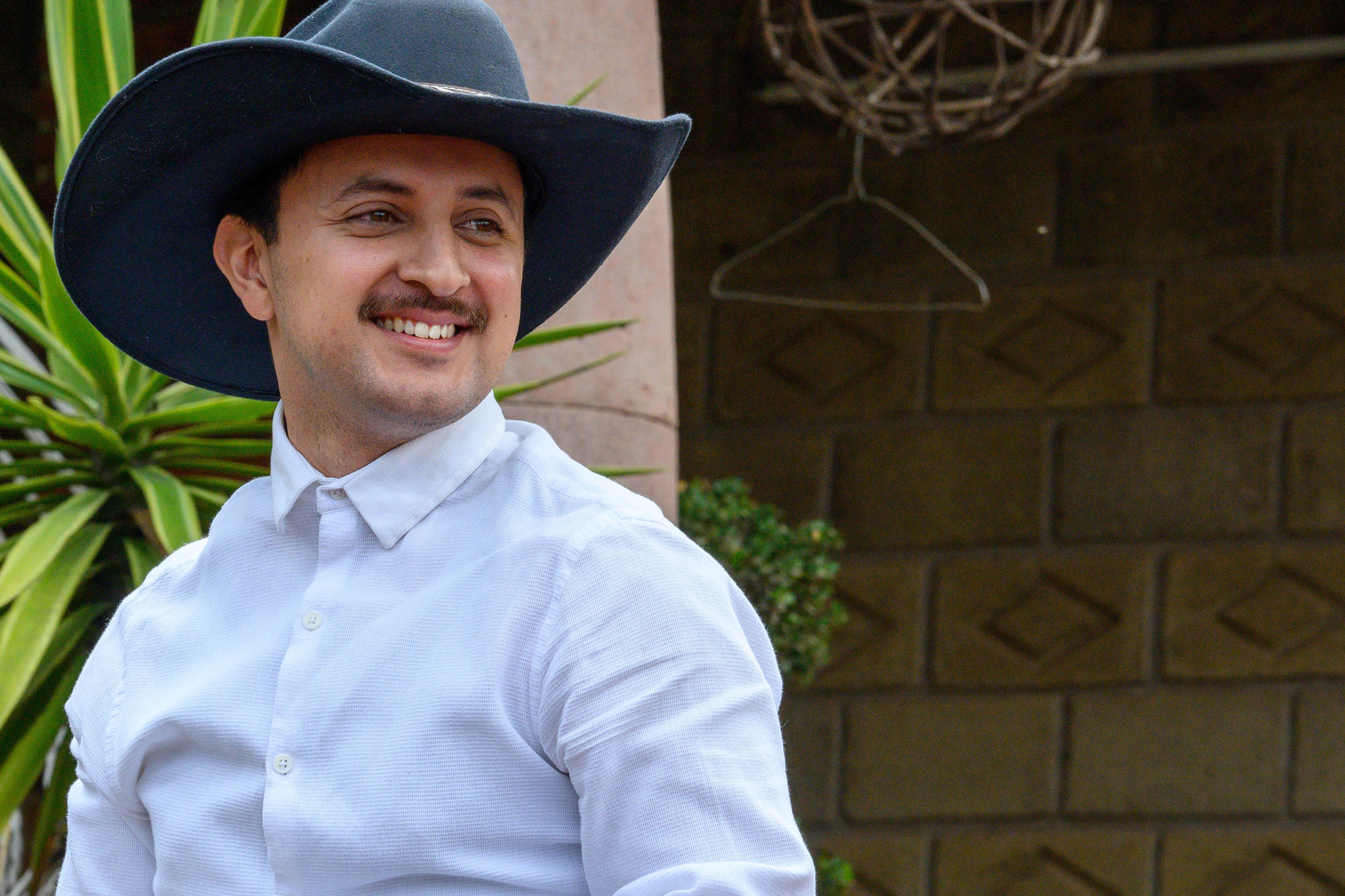 Portrait of a smiling man in a cowboy hat outdoors, exuding warmth and style