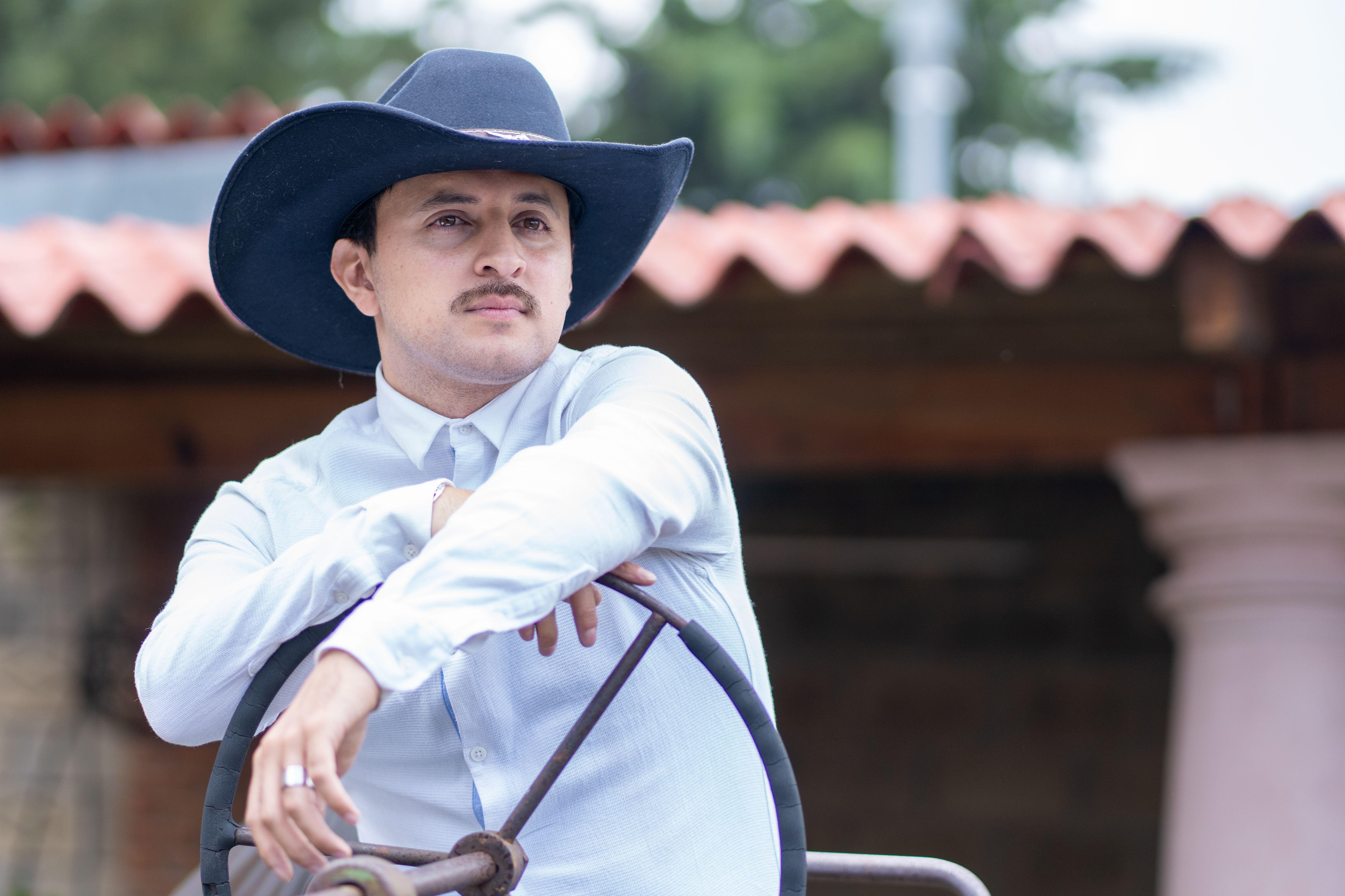 Portrait of a Caucasian male with a cowboy hat in Mexico City, combining urban style with traditional attire.