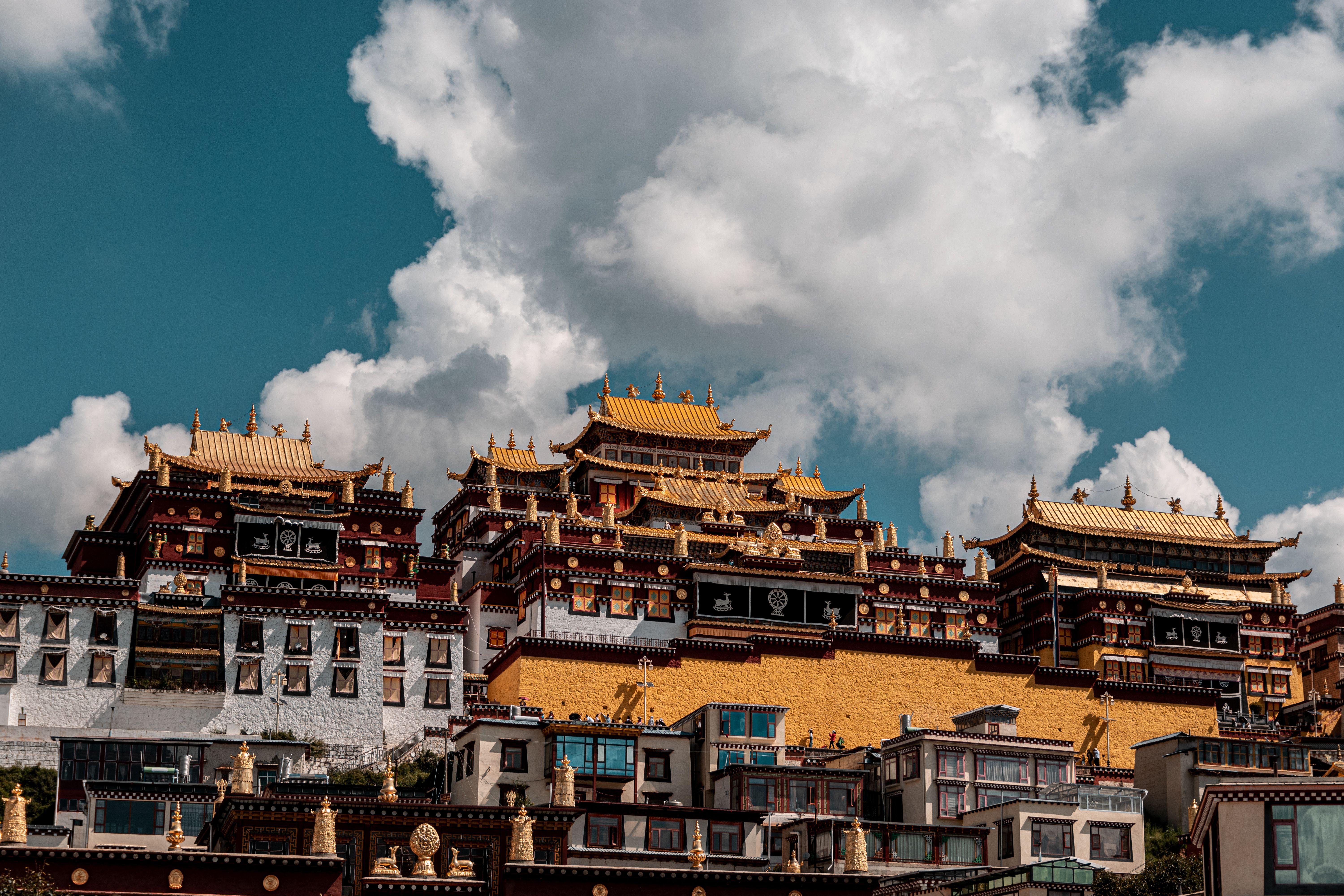 Majestic Buddhist temple complex with ornate architecture under a vibrant blue sky and clouds.