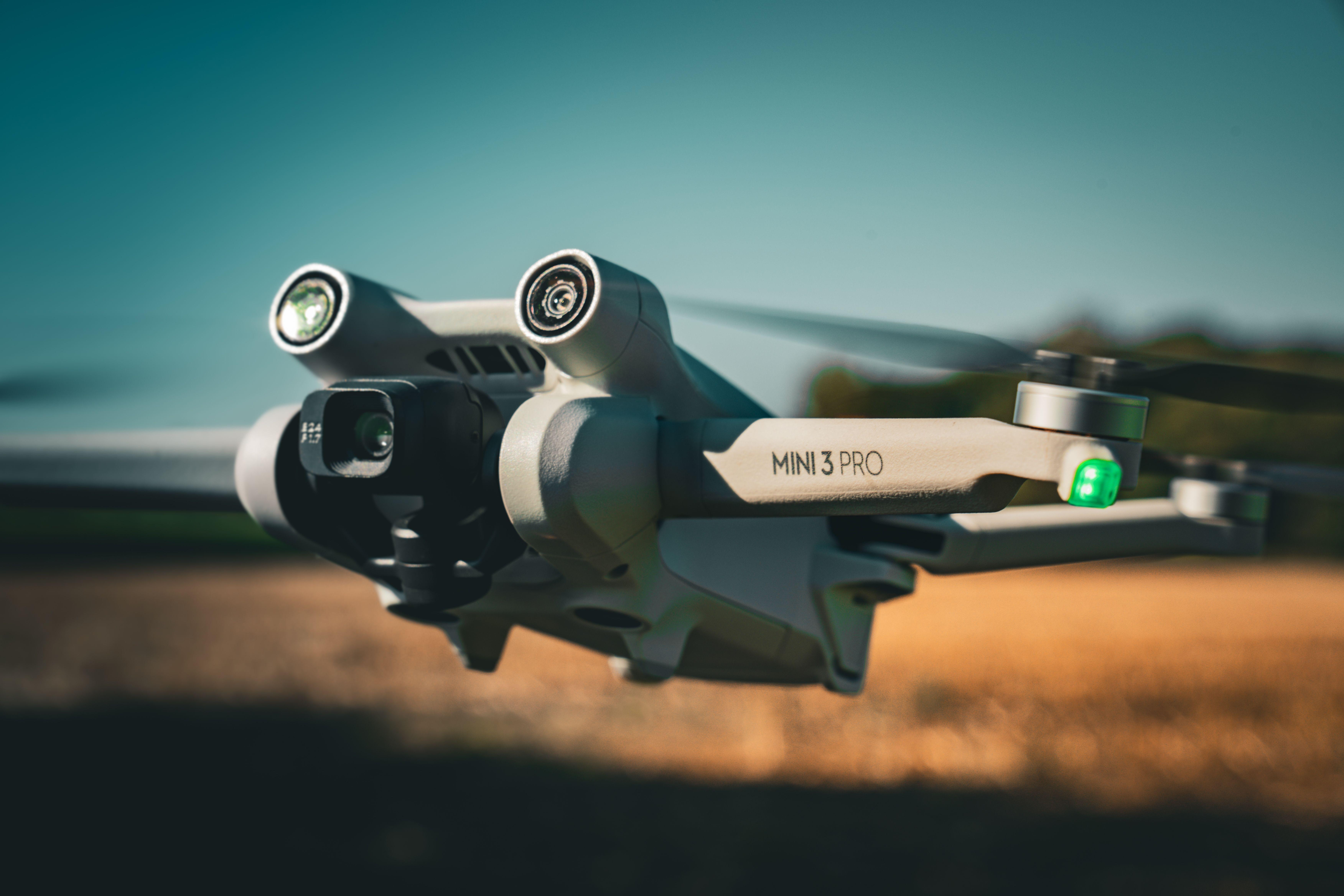 Detailed shot of a Mini 3 Pro drone flying outdoors, showcasing its camera and design.