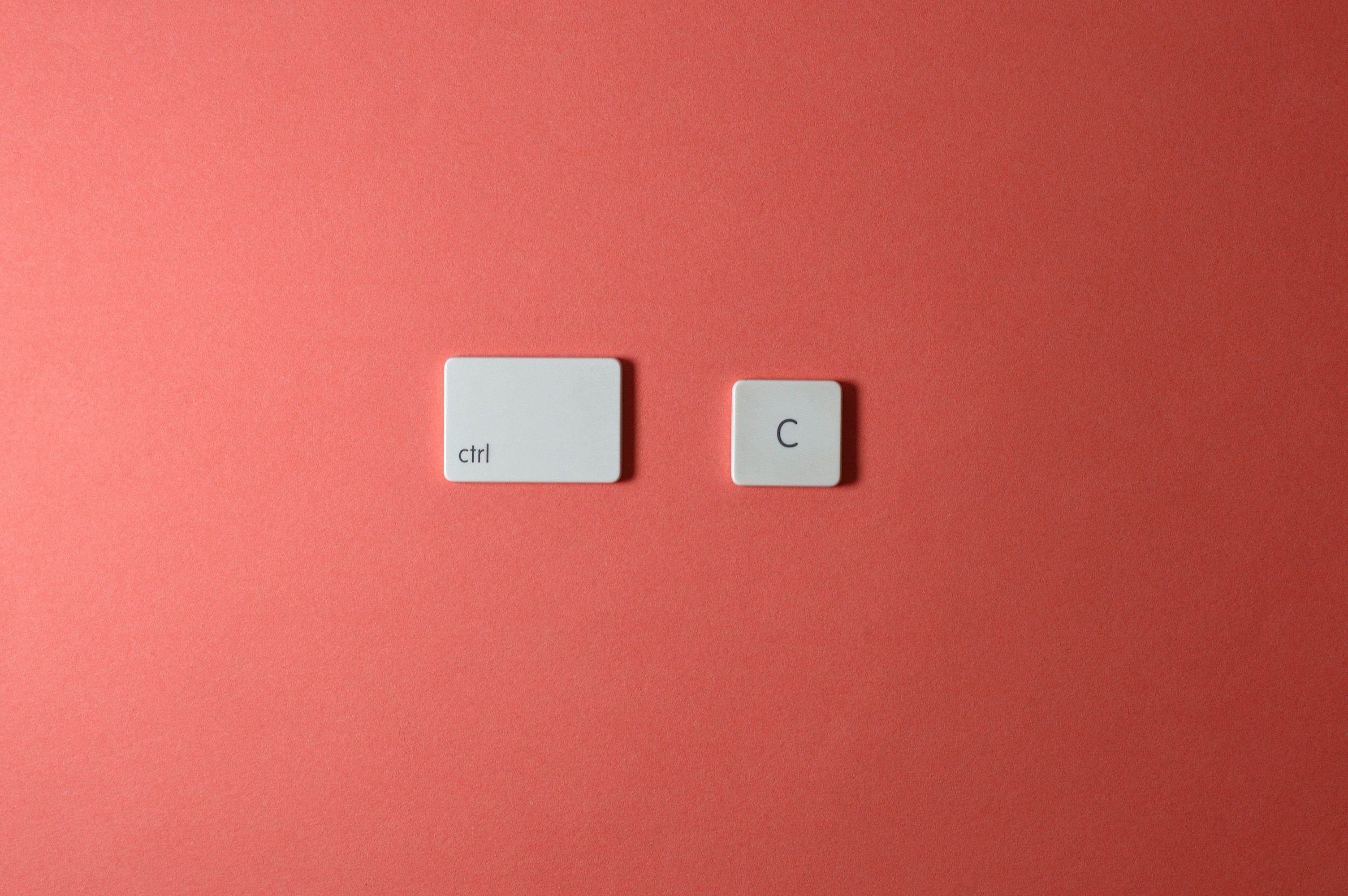 Simple keyboard keys Ctrl and C on a coral background, representing copy function.