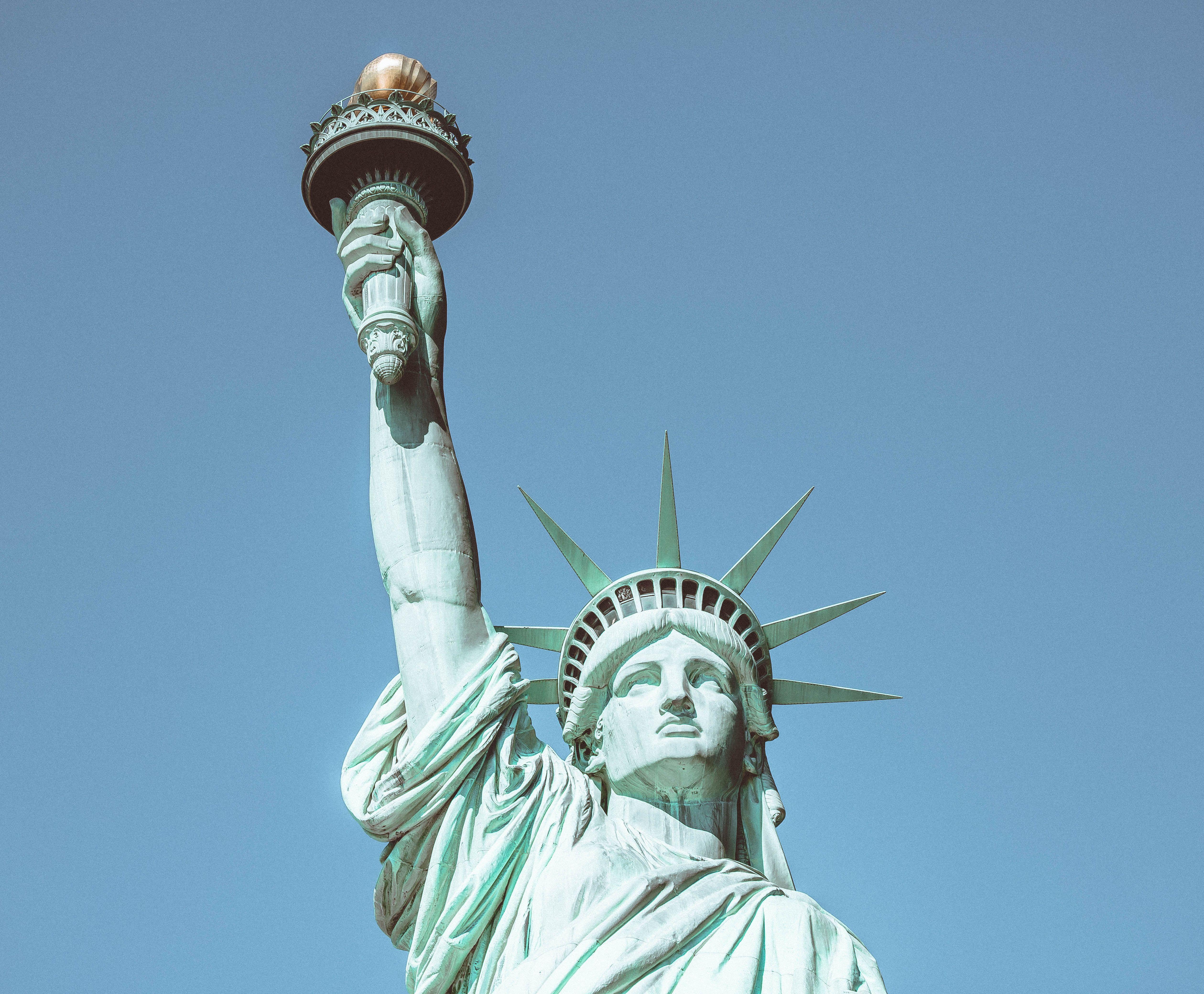 Close-up of the iconic Statue of Liberty against a clear blue sky, symbolizing freedom in New York City.