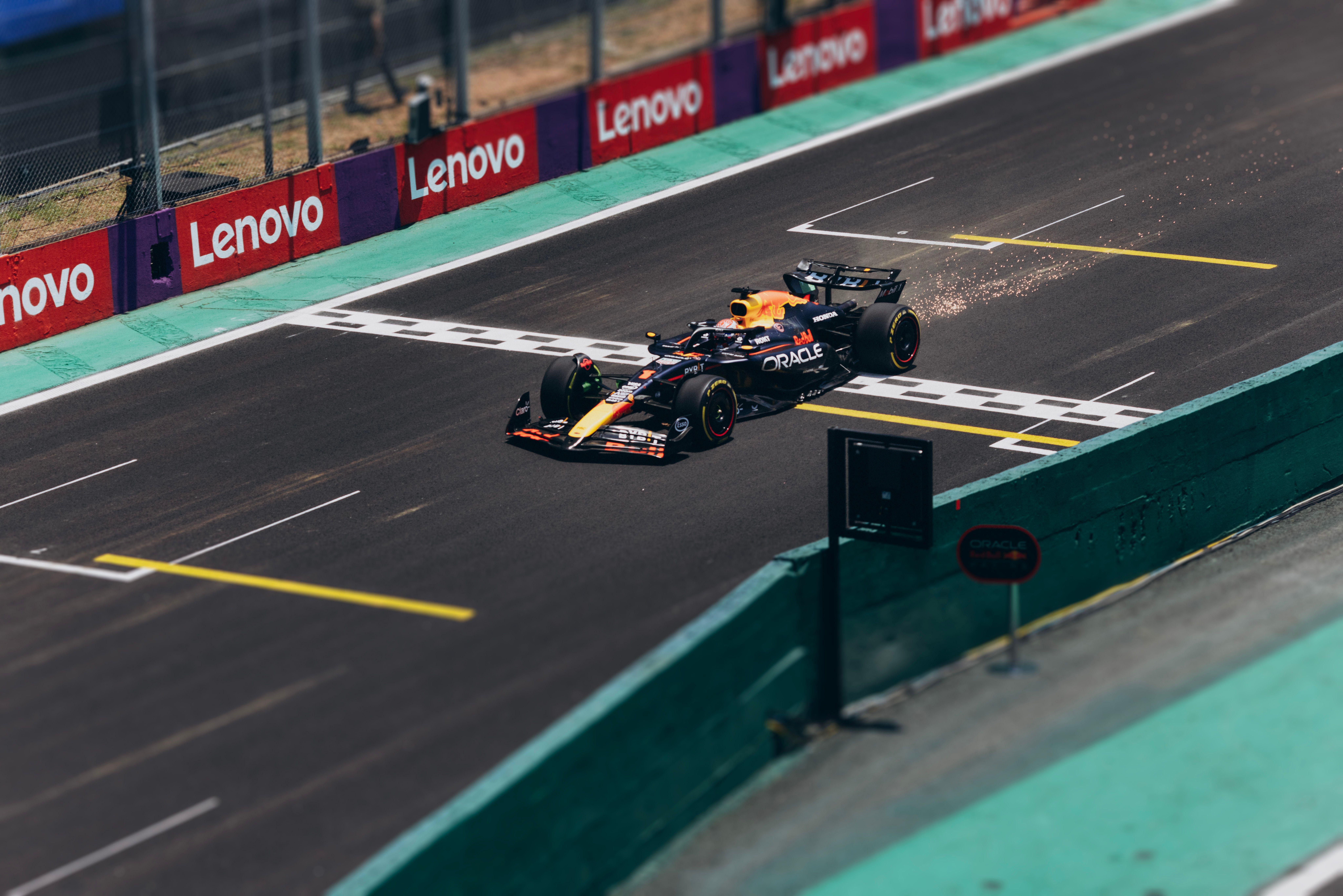 Formula 1 car speeding across the finish line on a racetrack, emitting sparks.