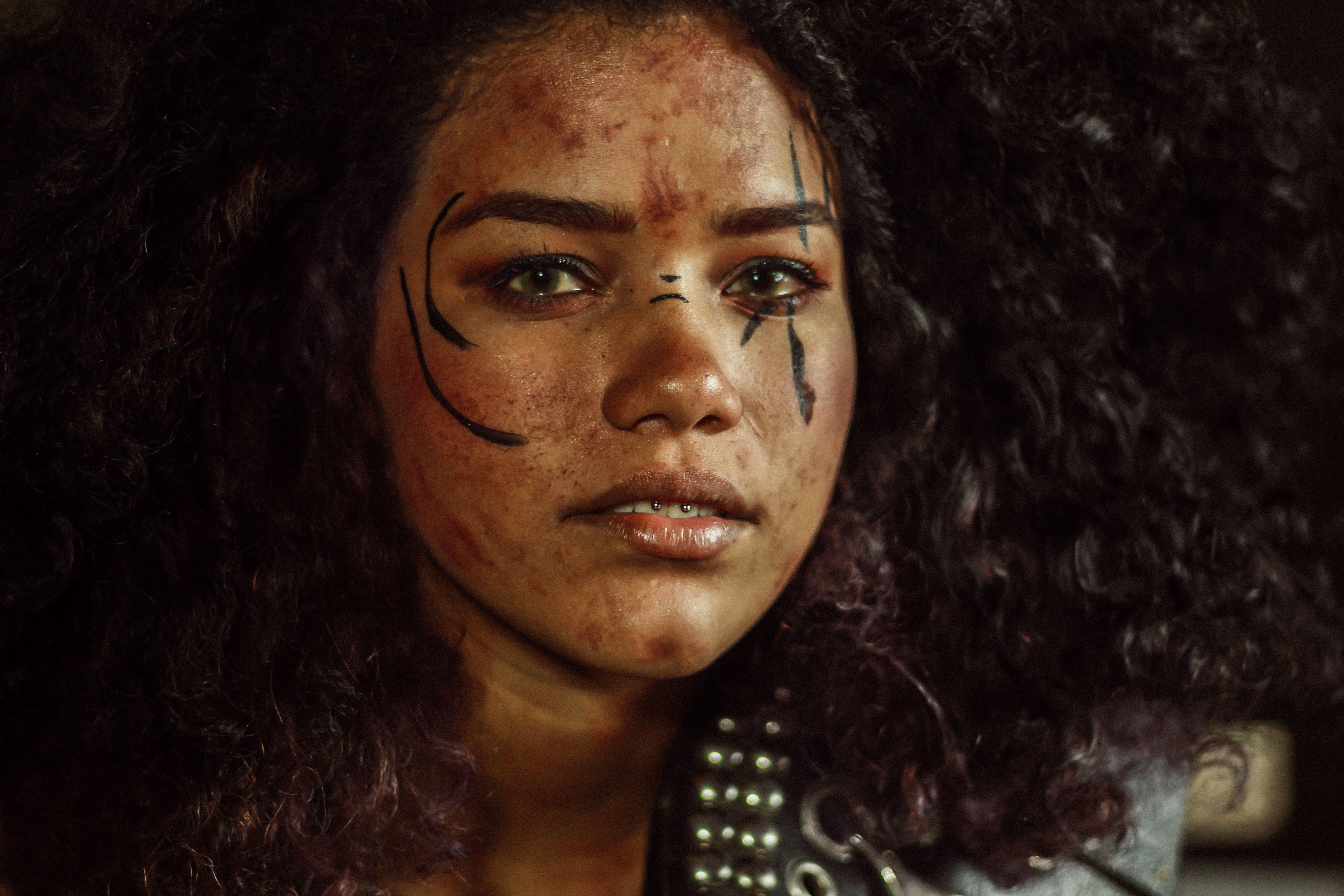 Close-up portrait of a woman with expressive makeup and curly hair in artistic lighting.