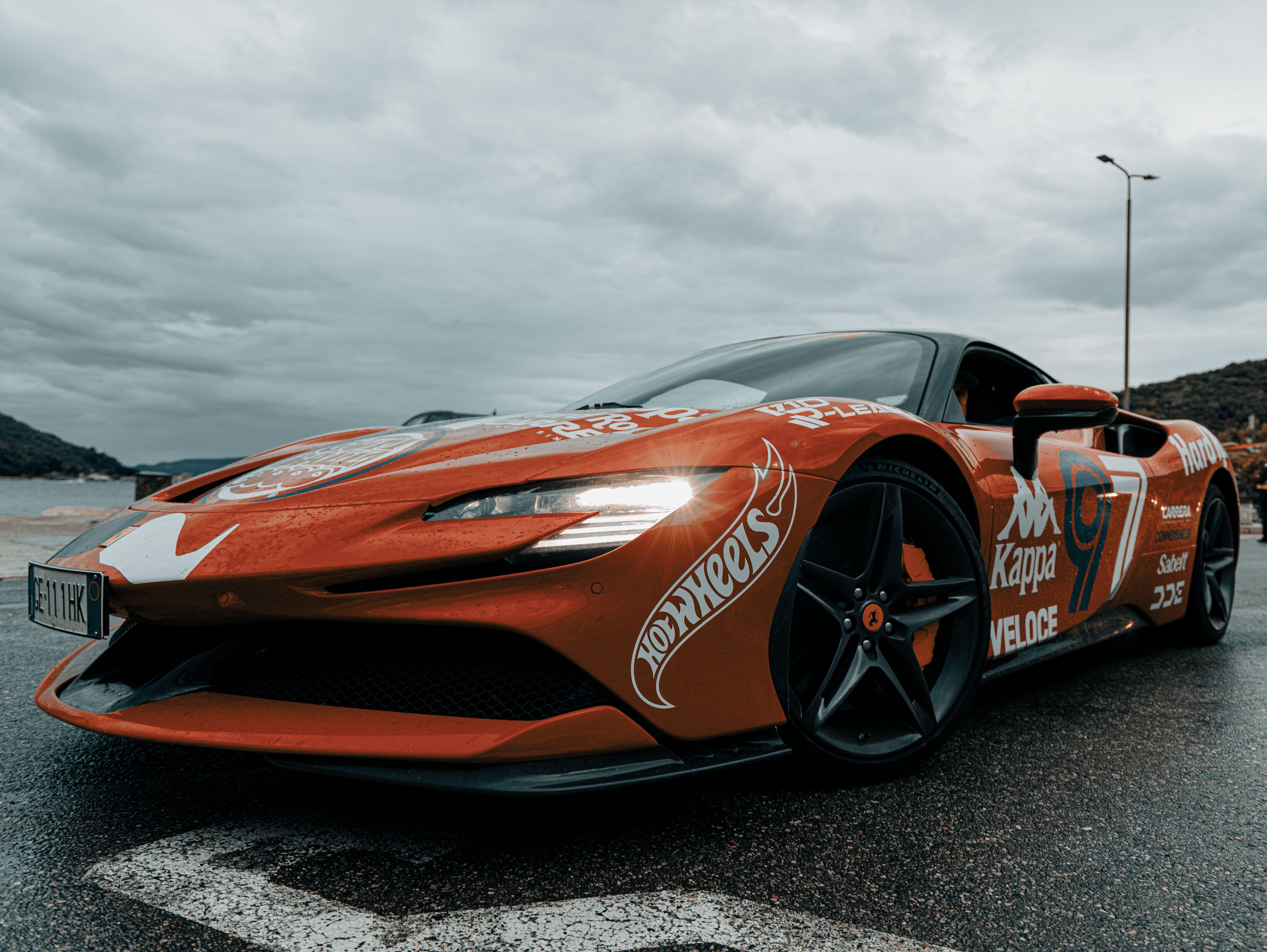 Dynamic shot of an electric sports car adorned with decals on a rainy day in Budva, Montenegro.