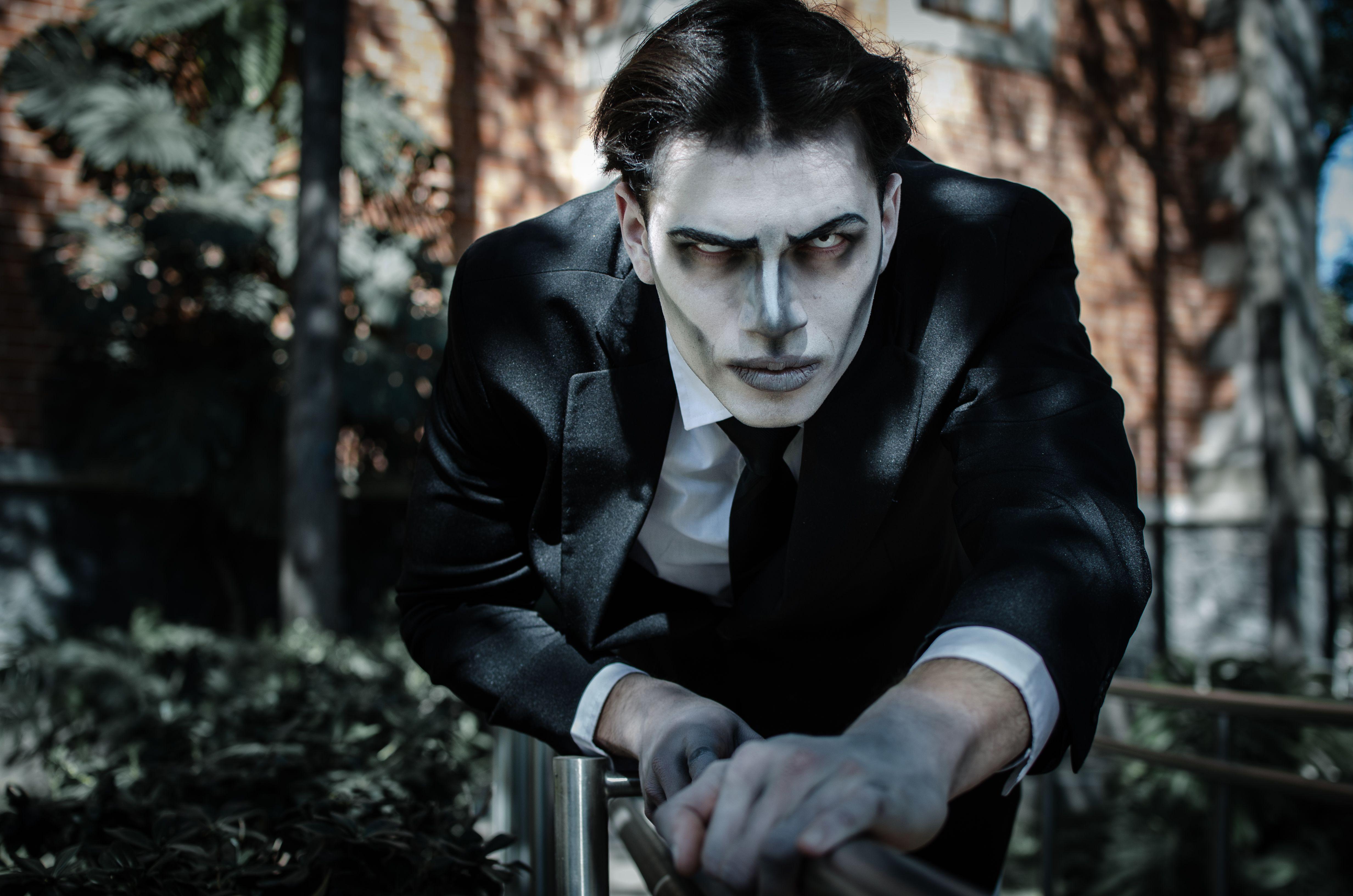 A man in a gothic Tim Burton-inspired costume poses dramatically outdoors, ideal for Halloween themes.