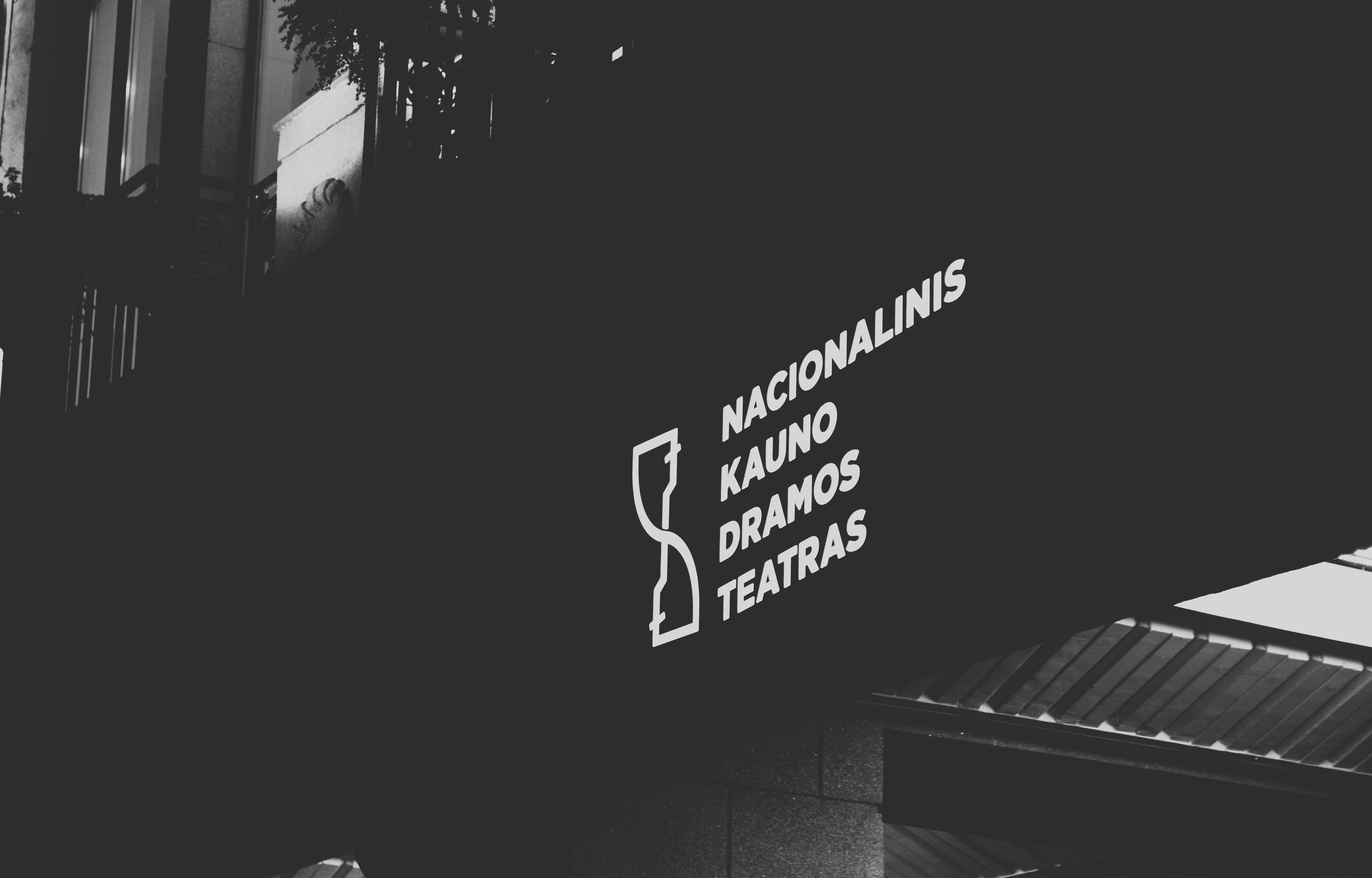 Illuminated signage of Kaunas Drama Theatre in black and white low angle shot.