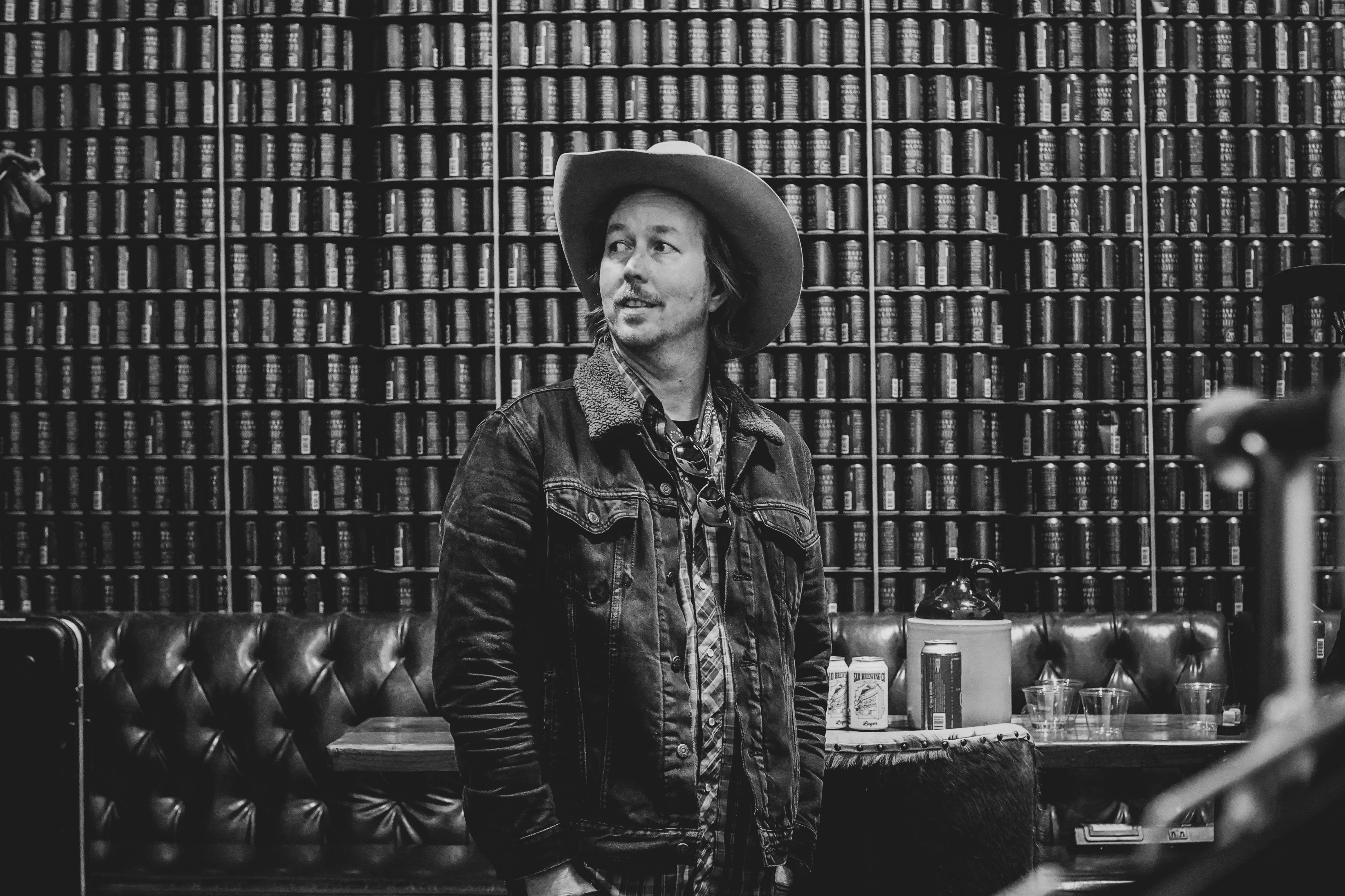Artistic black and white portrait of a man in a cowboy hat indoors.