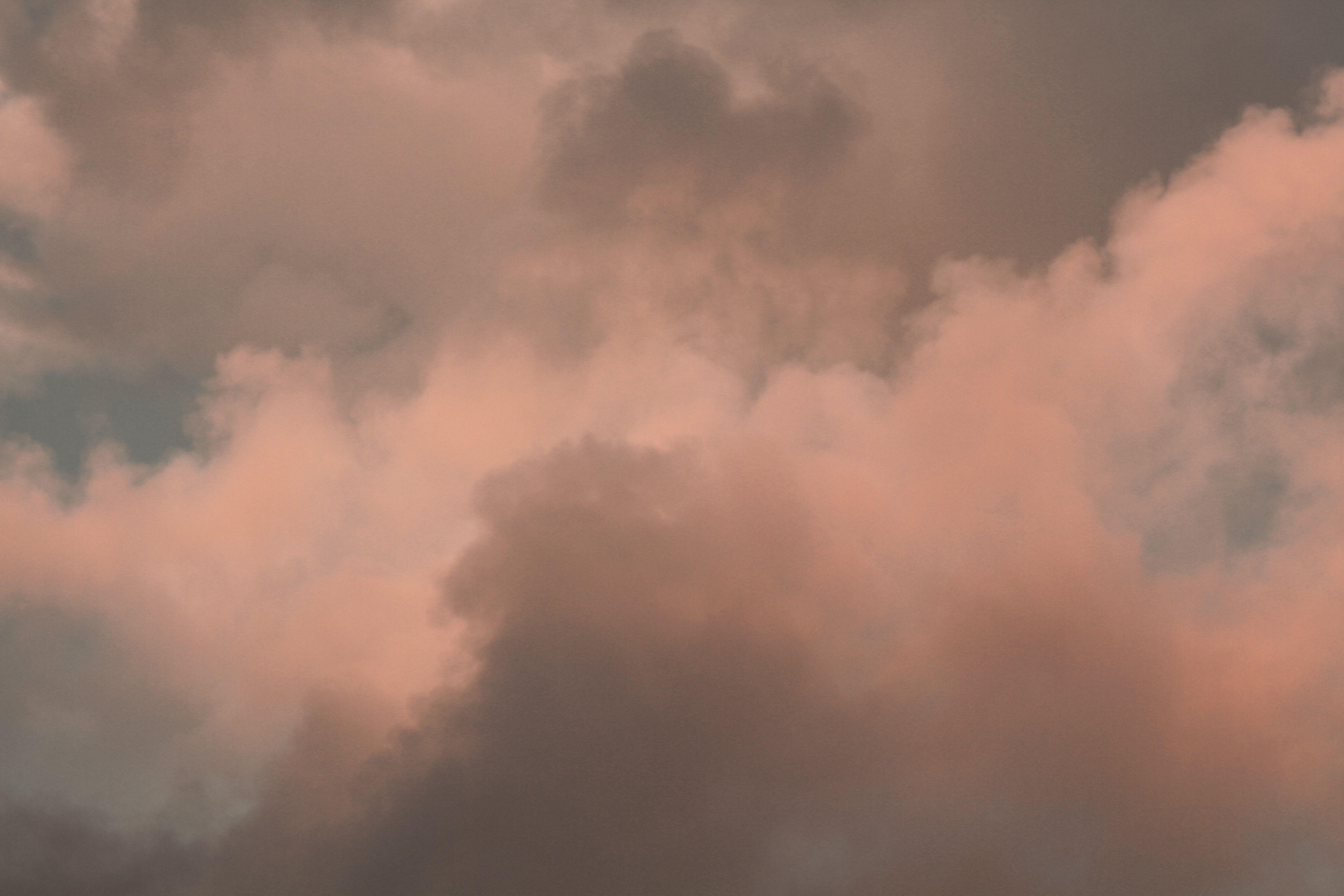 A serene and dramatic cloudscape featuring soft hues of pink and gray, capturing a tranquil sky moment.