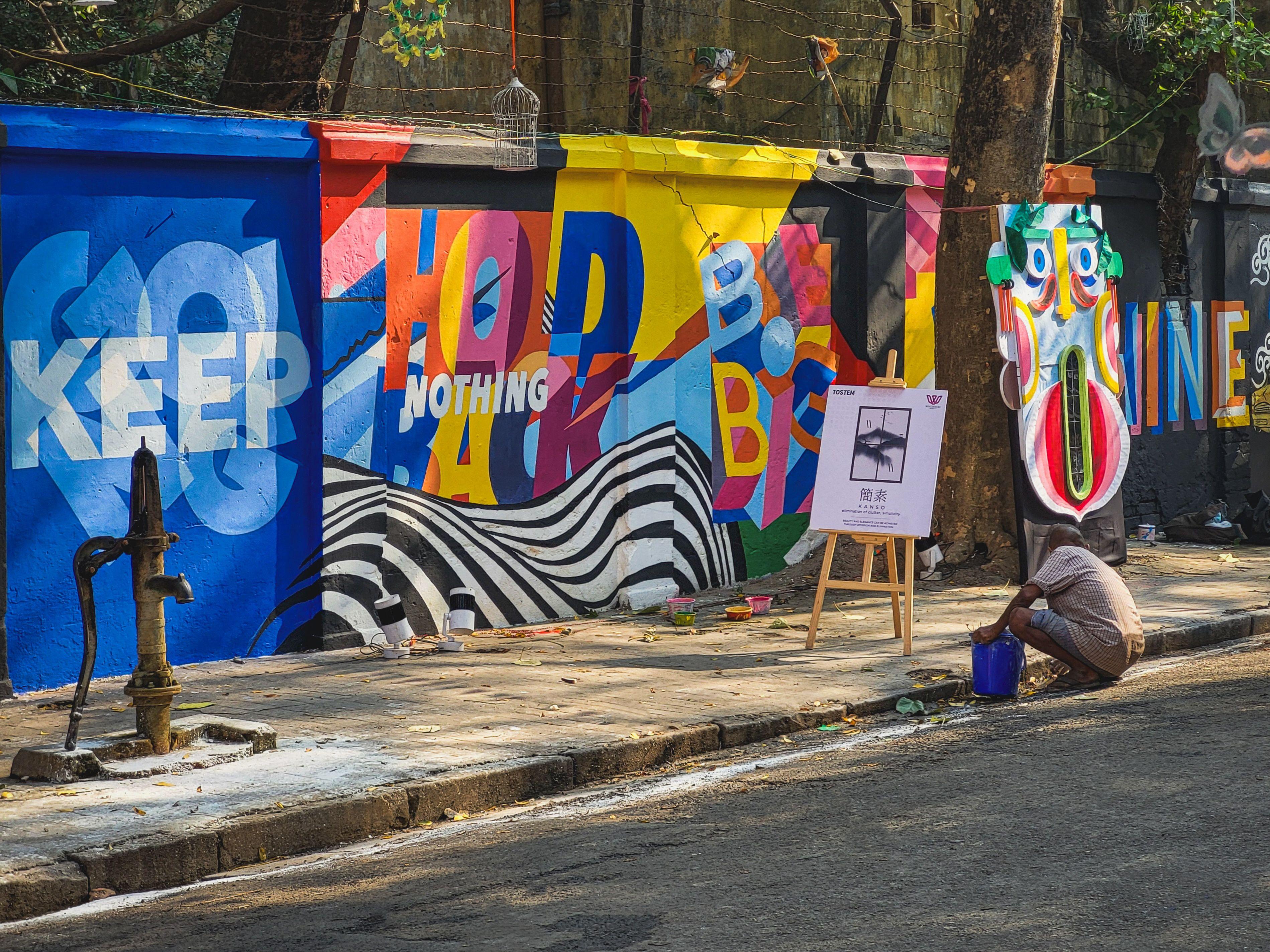Vibrant street art with person painting on Kolkata sidewalk, India.